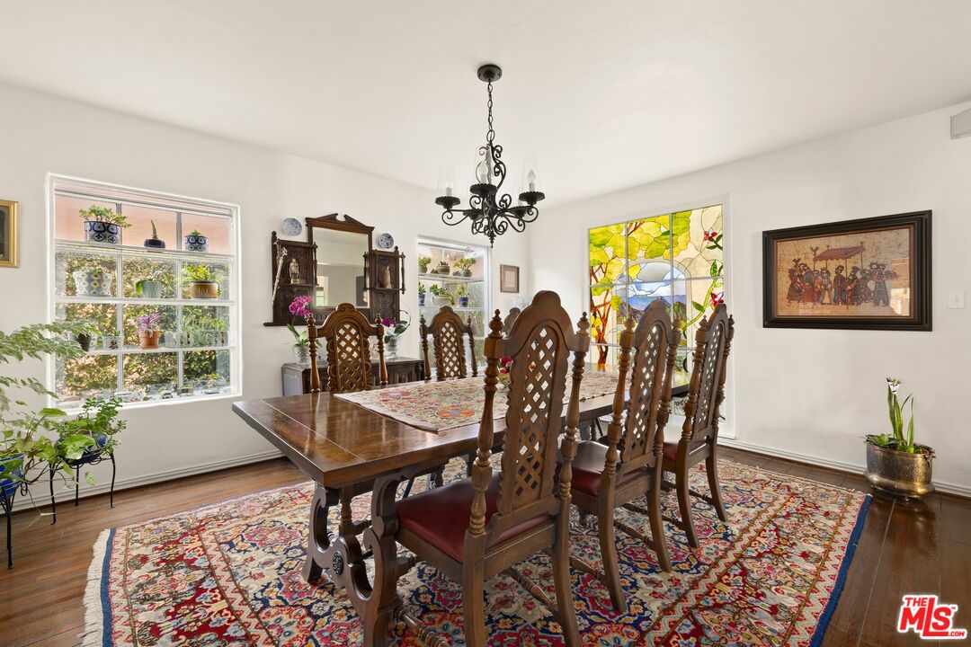 Dining room with a carved wood table, patterned rug, and colorful stained-glass window.