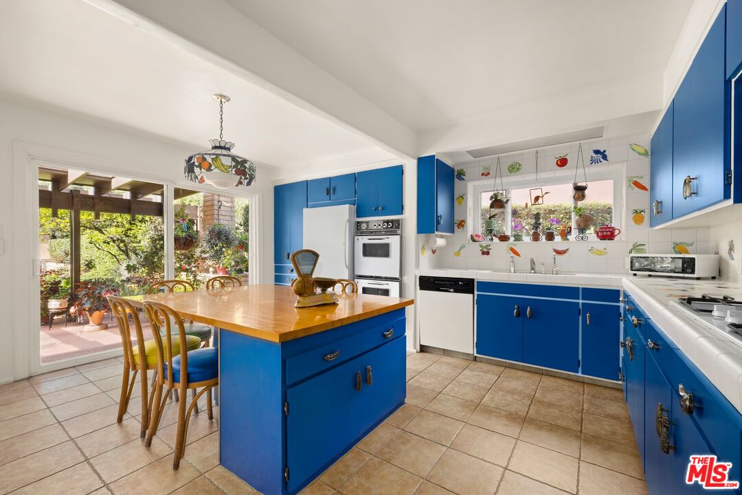 Kitchen with blue cabinets, a wood-topped island, and sliding doors opening to a leafy patio.