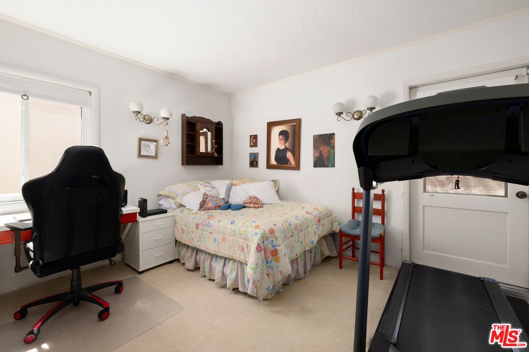 Furnished bedroom with a floral bed, desk and gaming chair, and a treadmill.