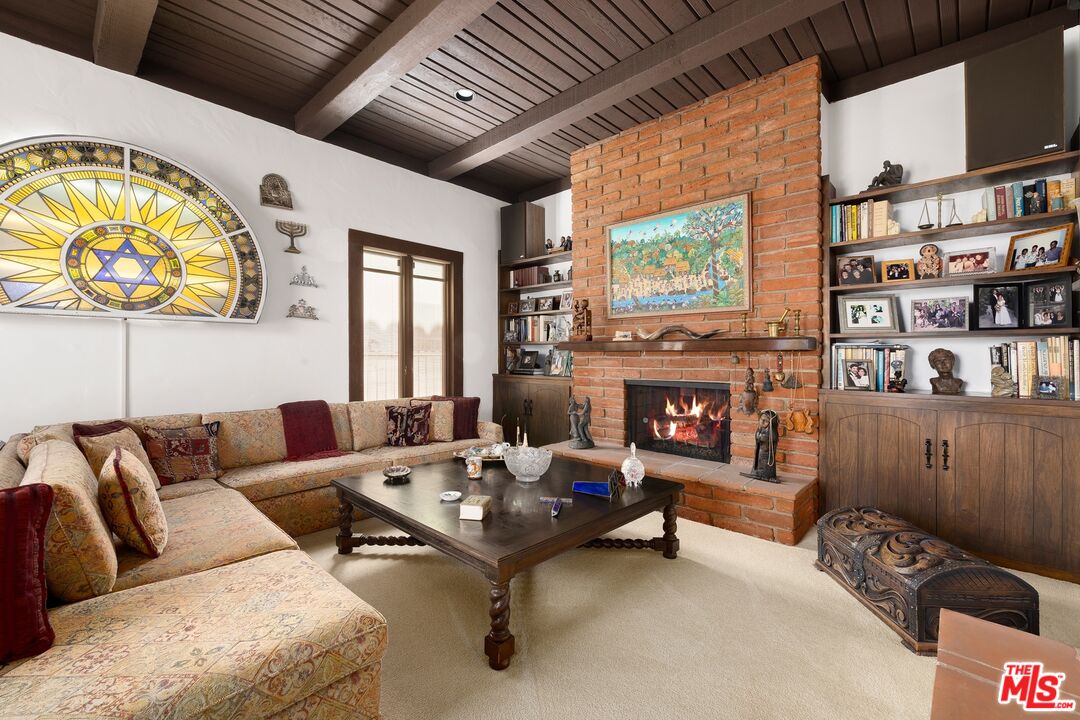 Living room with a brick fireplace, exposed wood-beam ceiling, and stained-glass wall decoration.