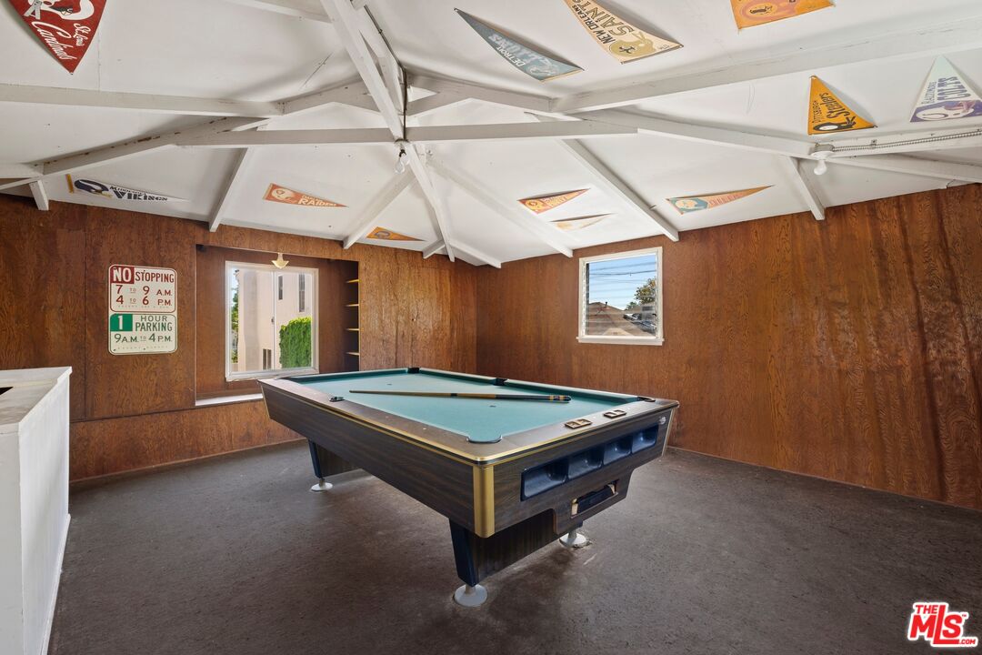 Game room with a pool table, wood-paneled walls, and pennants decorating the exposed ceiling beams.