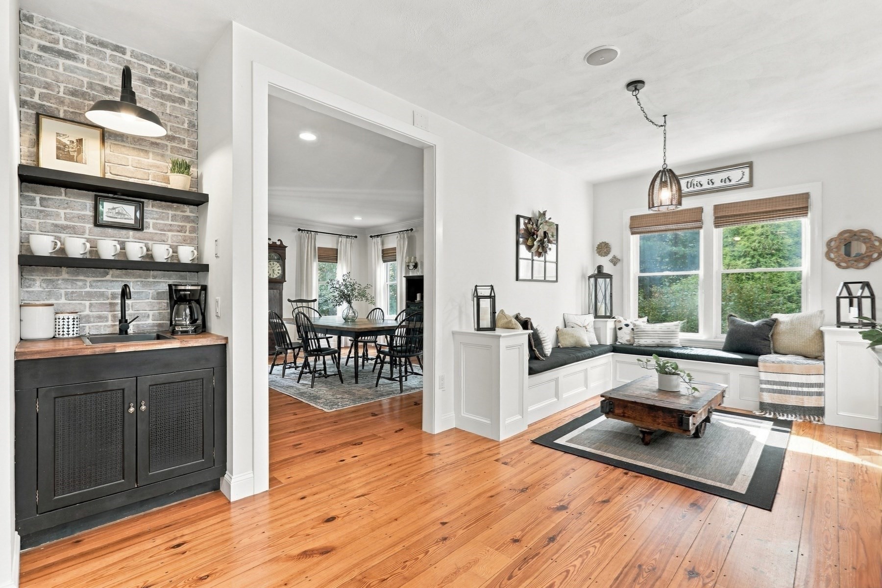 Living room with a built-in window seat, brick-backed coffee station, and warm wood floors.