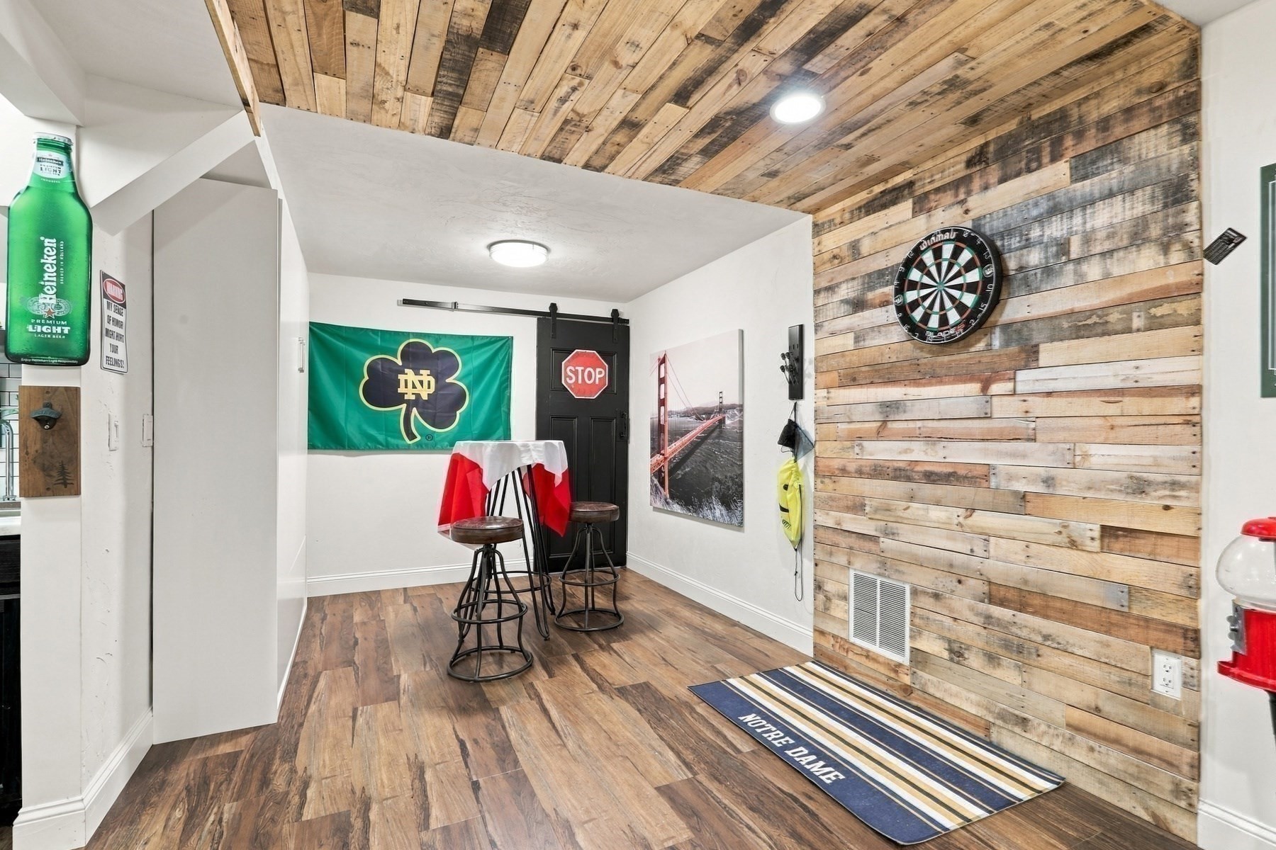 Recreation room with a dartboard, rustic wood walls and ceiling, and Notre Dame decor.