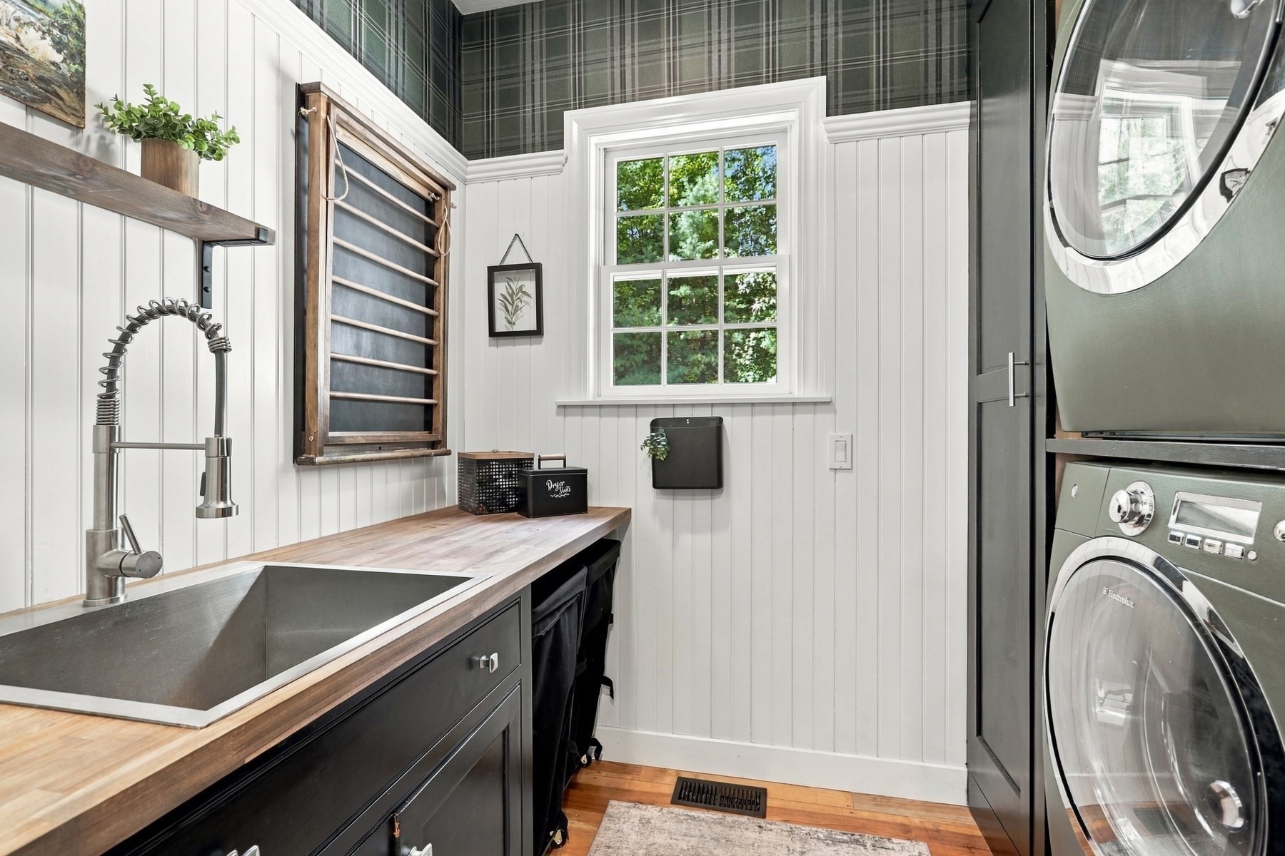 Laundry room with a deep utility sink, wood countertop, and stacked washer and dryer.