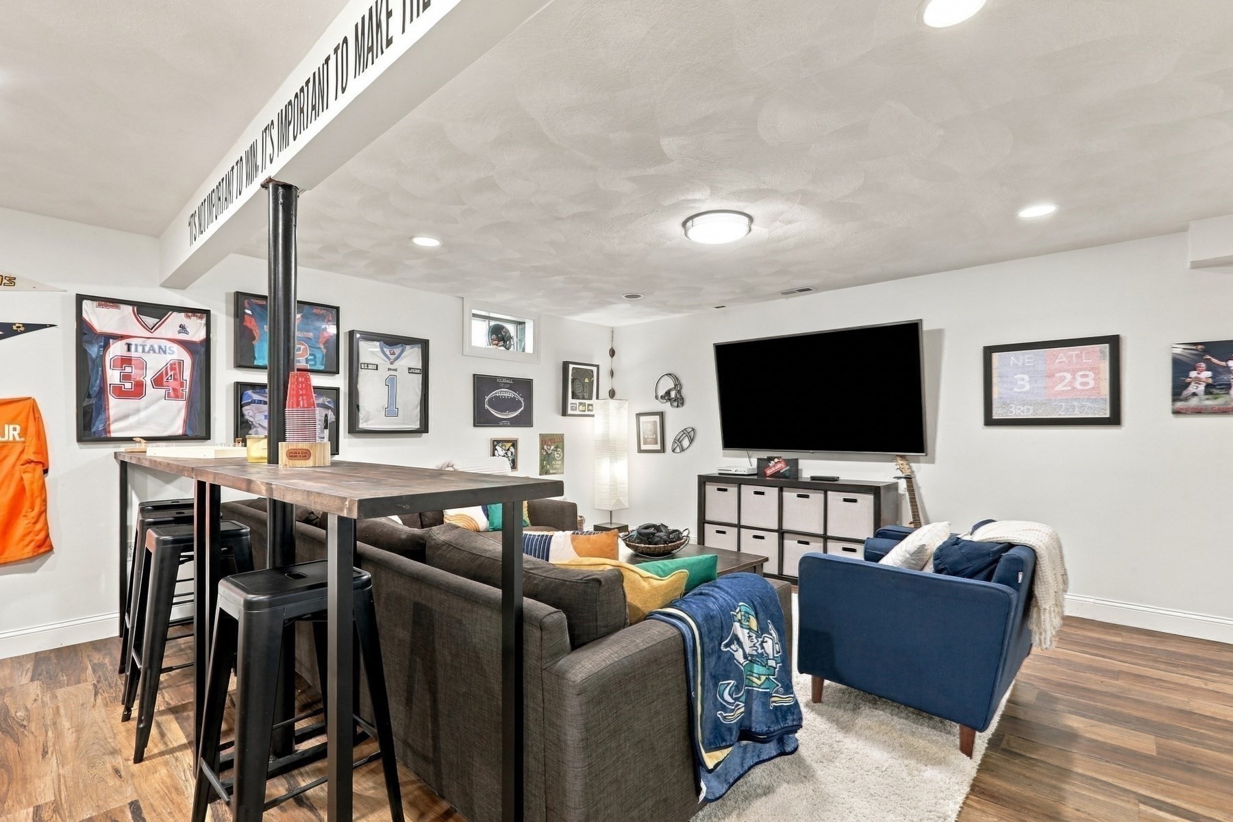 Furnished basement media room with a large television, sectional seating, and framed sports memorabilia.