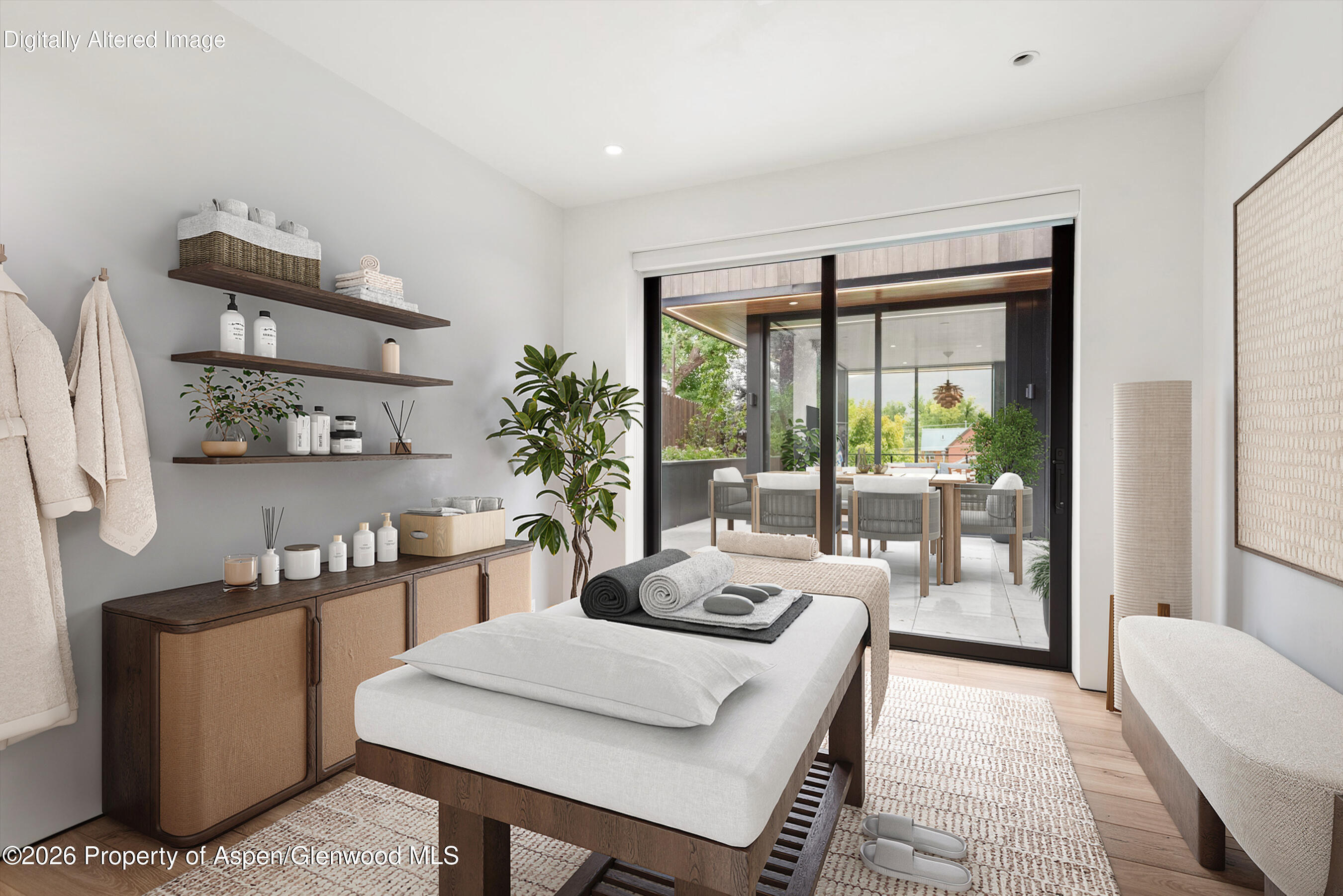 Spa treatment room with a massage table and open sliding doors to a covered patio.