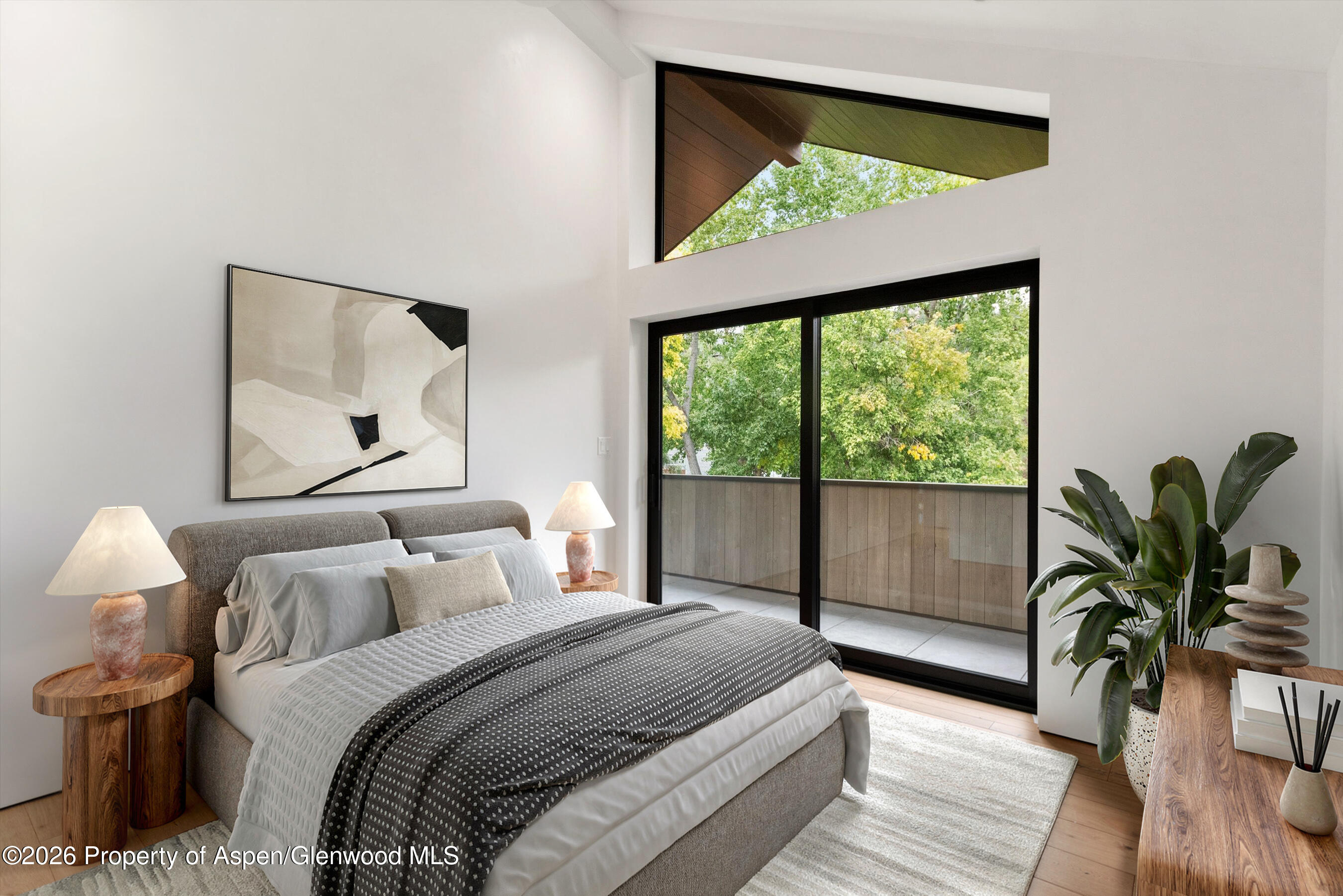 Furnished bedroom with a large bed and black-framed glass doors opening onto a balcony.