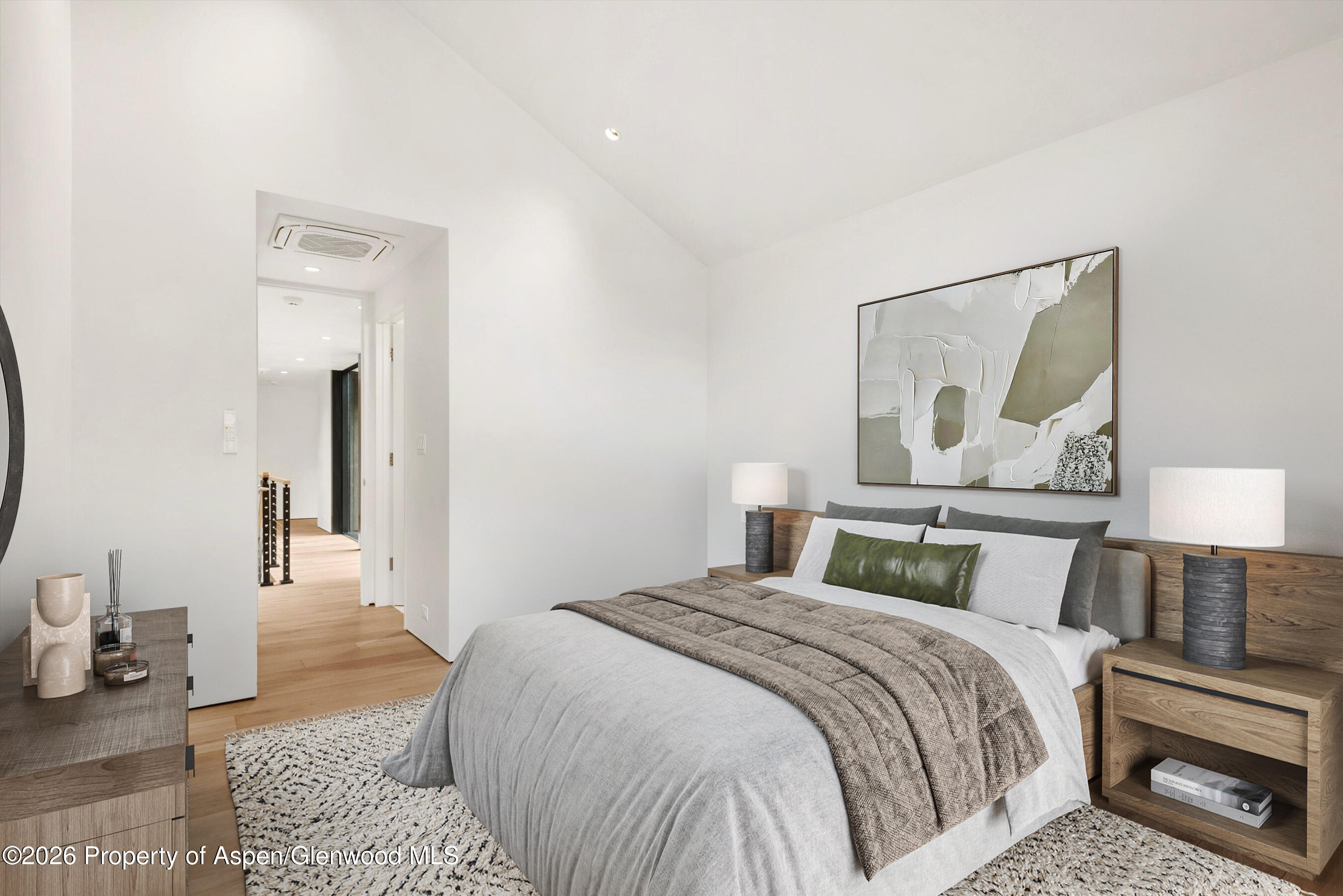 Staged bedroom with a king-size bed, wood headboard, abstract art, and light wood flooring.