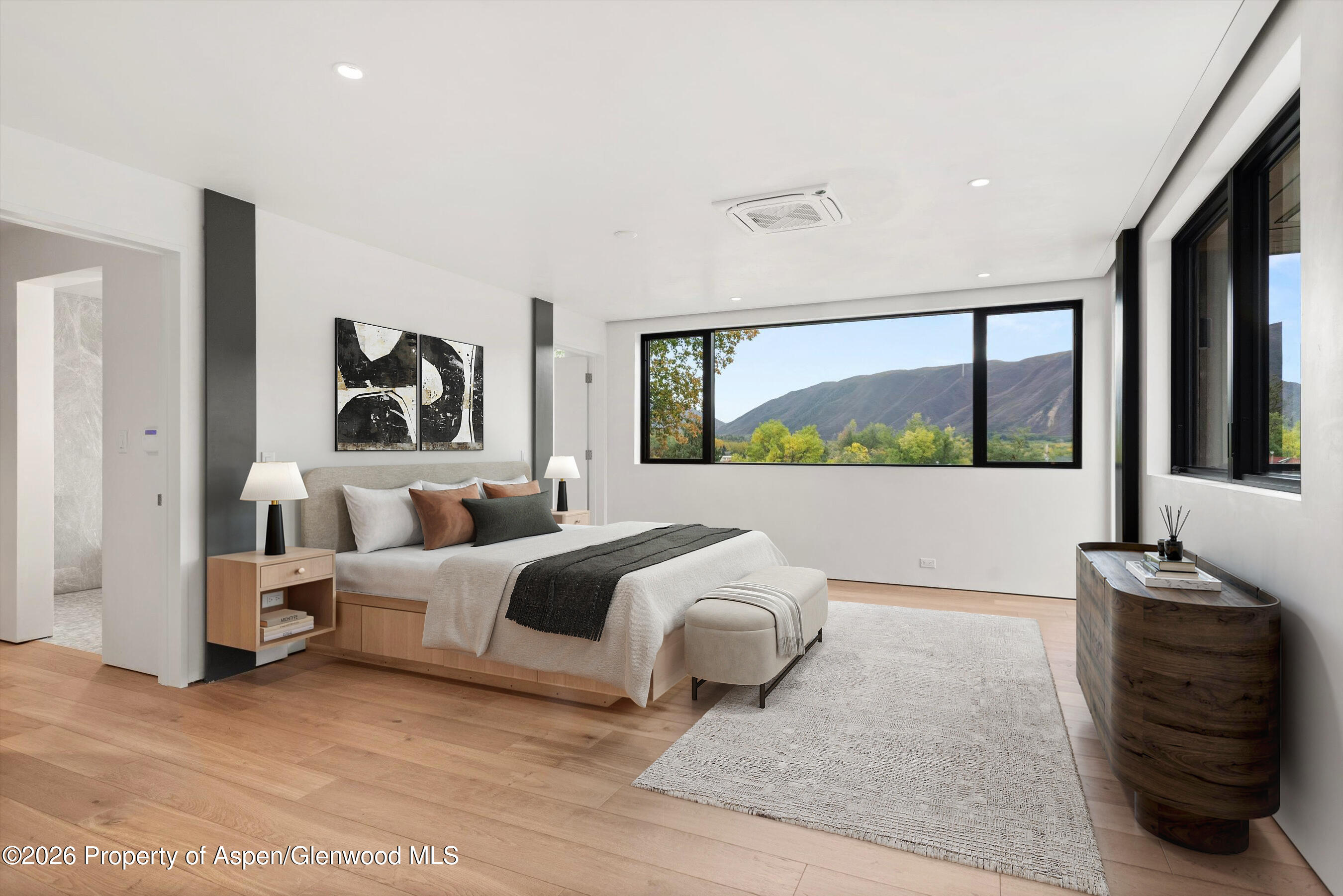 Modern bedroom with a king bed and wide windows overlooking a mountain.