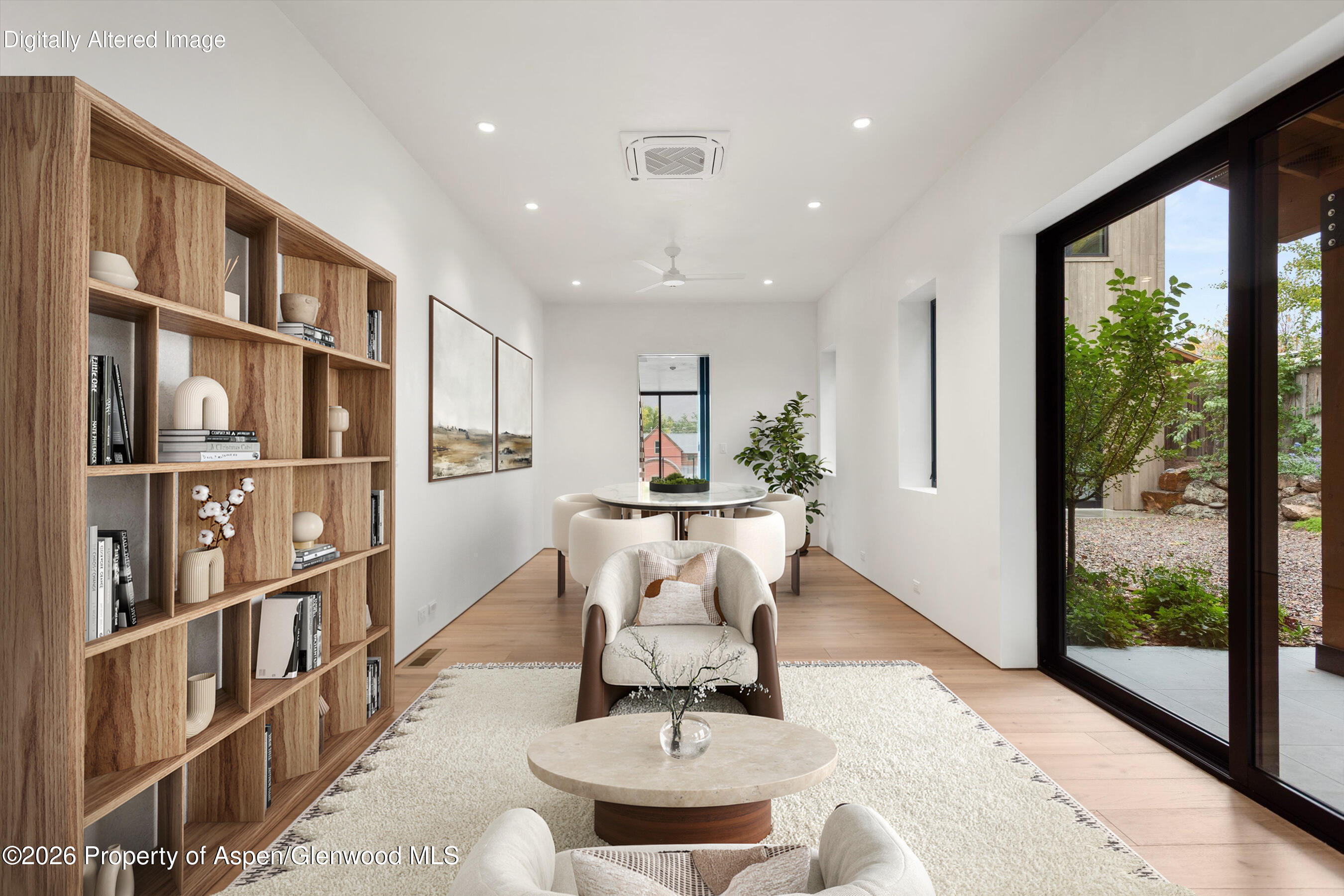 Furnished living and dining room with a wood bookcase and sliding glass doors to a courtyard.
