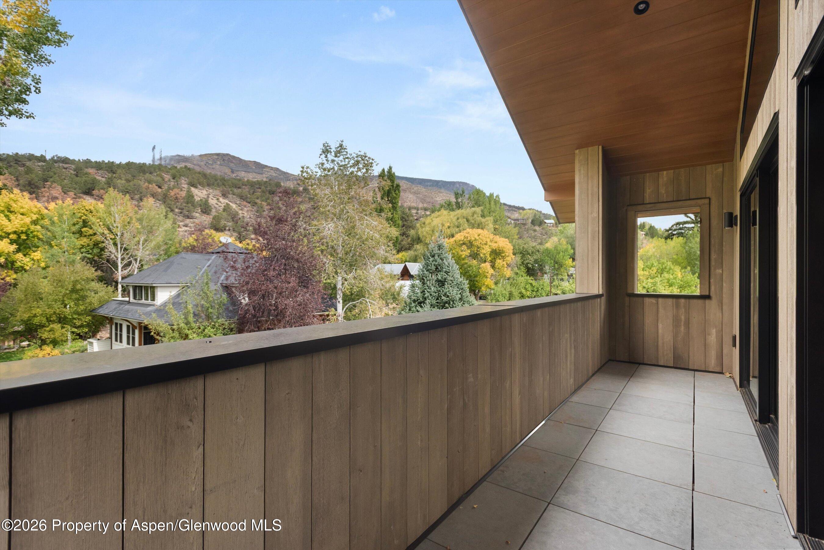 Tiled balcony overlooking autumn trees, neighboring homes, and low mountains