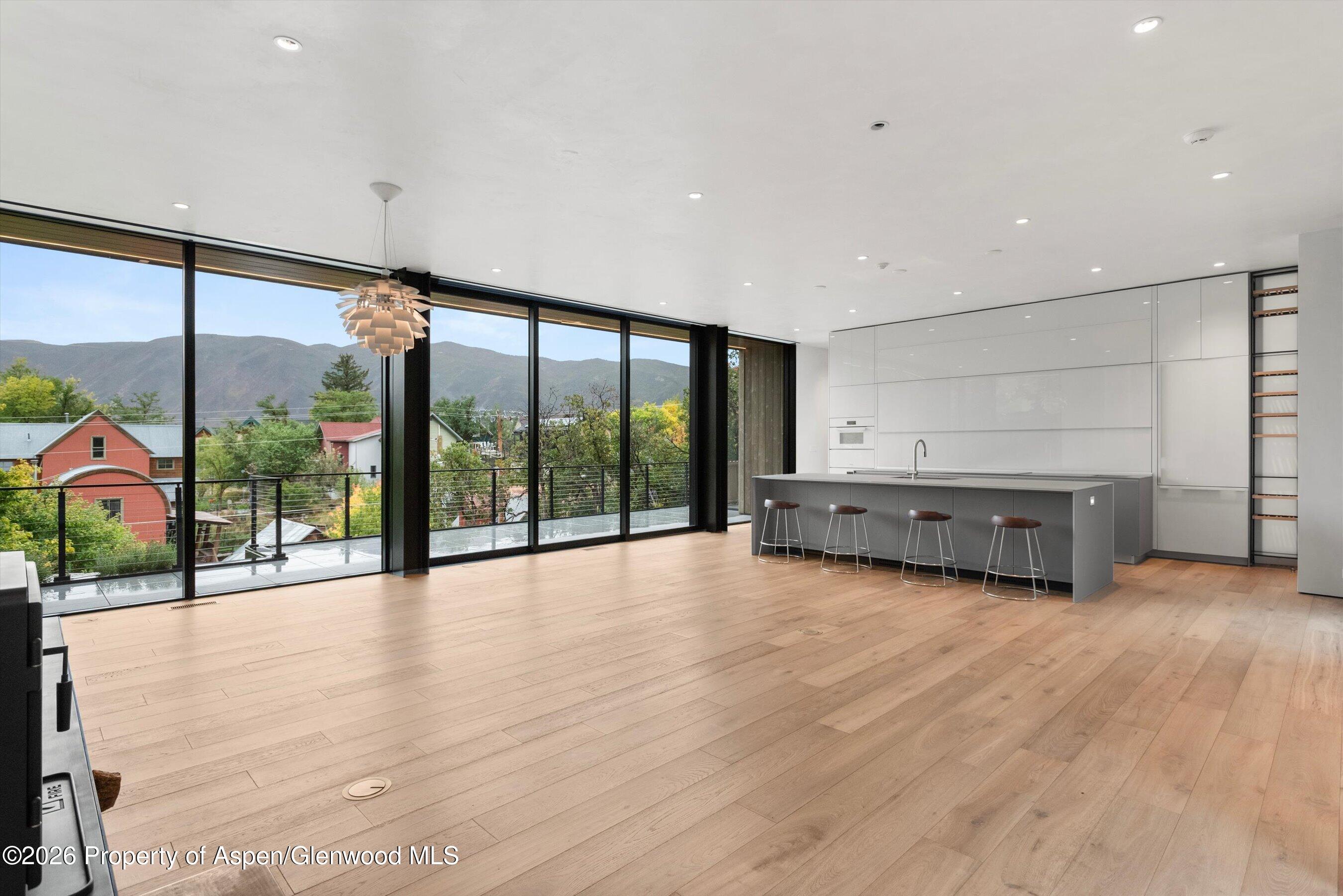 Modern kitchen with a gray island and mountain views through floor-to-ceiling windows.
