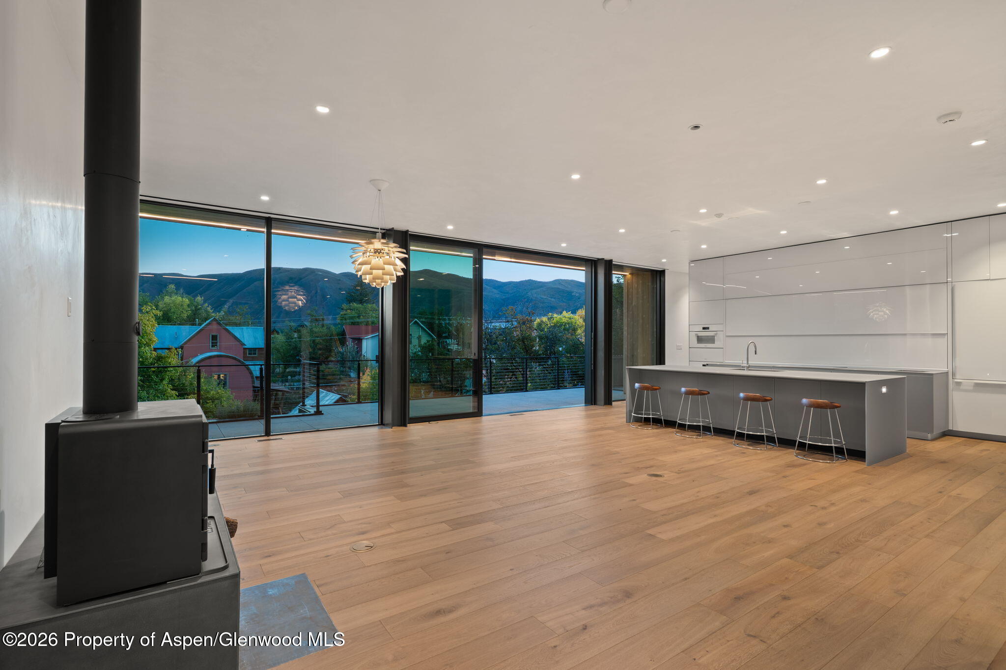 Modern kitchen with a gray island and mountain views through floor-to-ceiling glass doors.