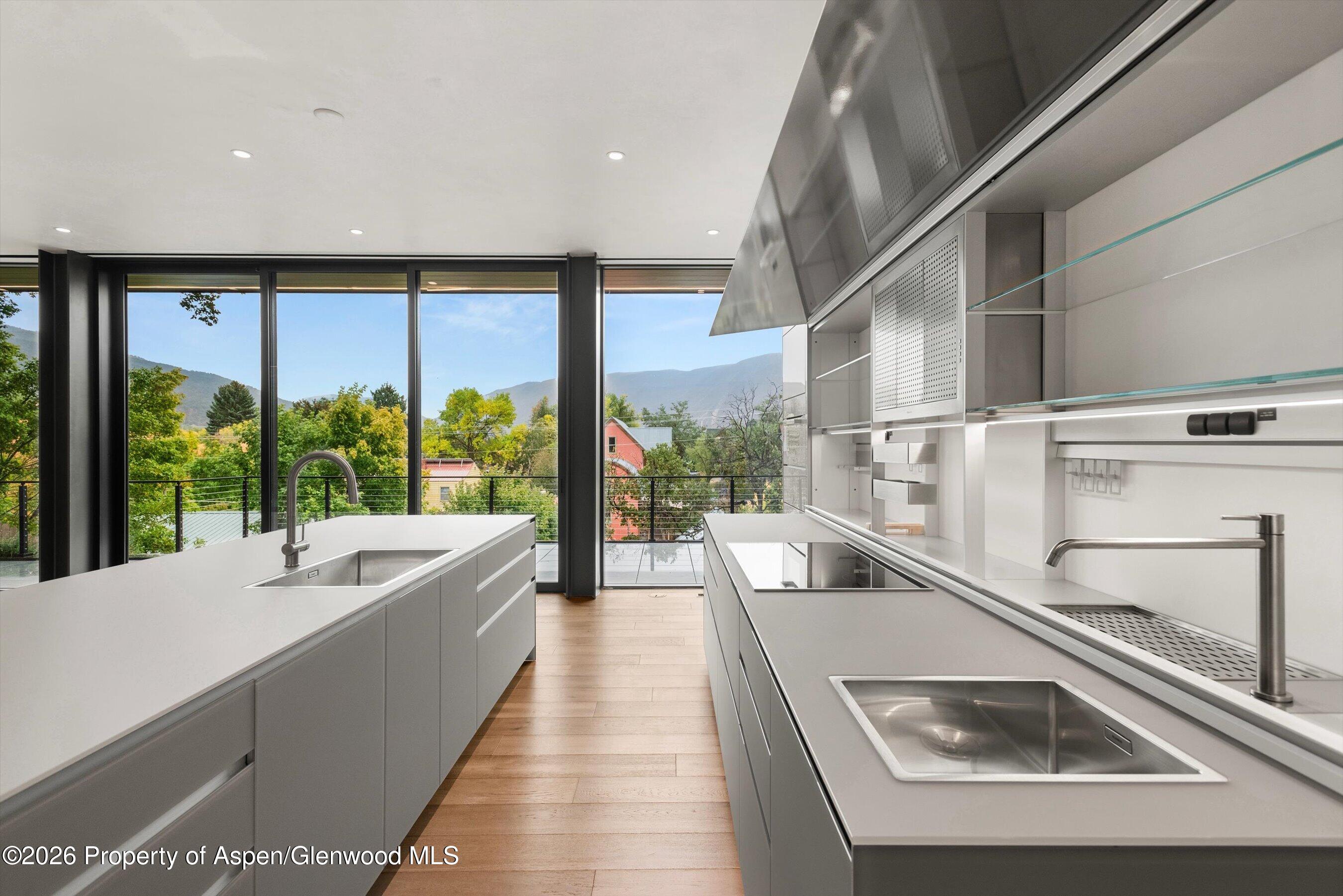 Modern kitchen with dual islands and mountain views through floor-to-ceiling windows.