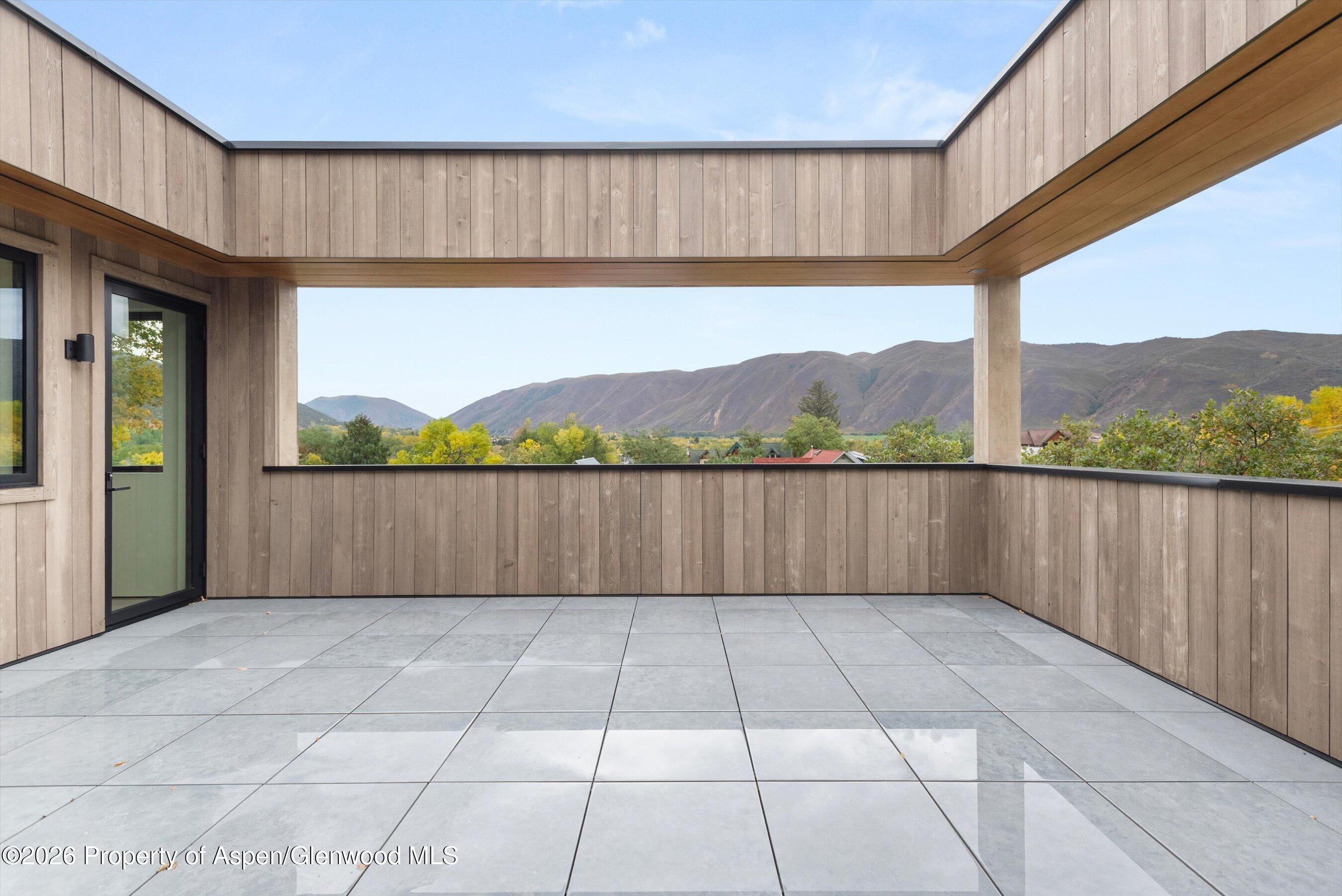 Tiled rooftop patio framed in wood, with an open view of autumn trees and mountain ridges.