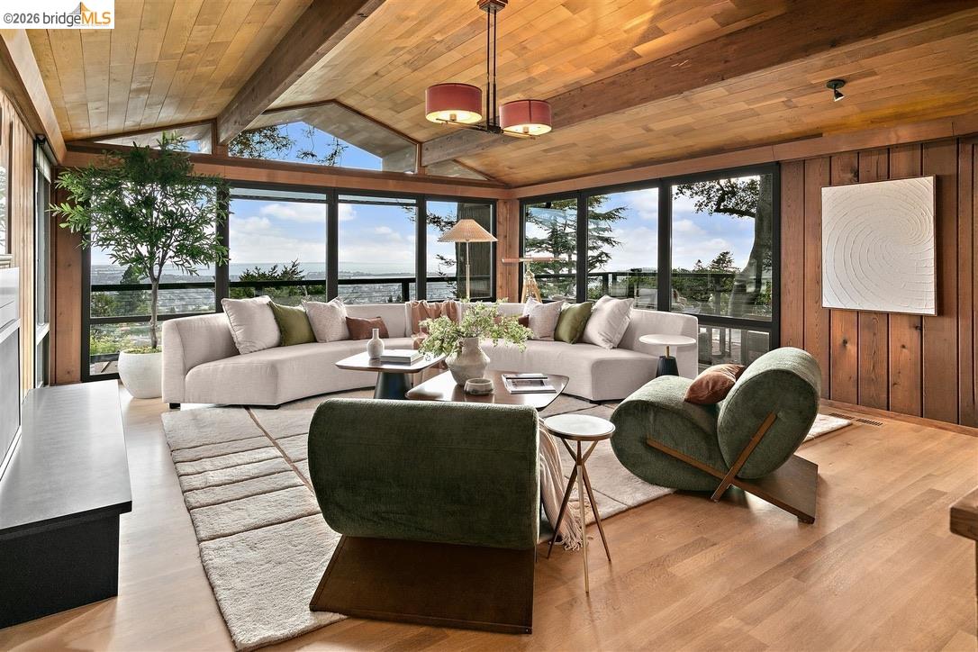 Living room with vaulted wood ceiling, corner windows, cream sectional, and green lounge chairs.