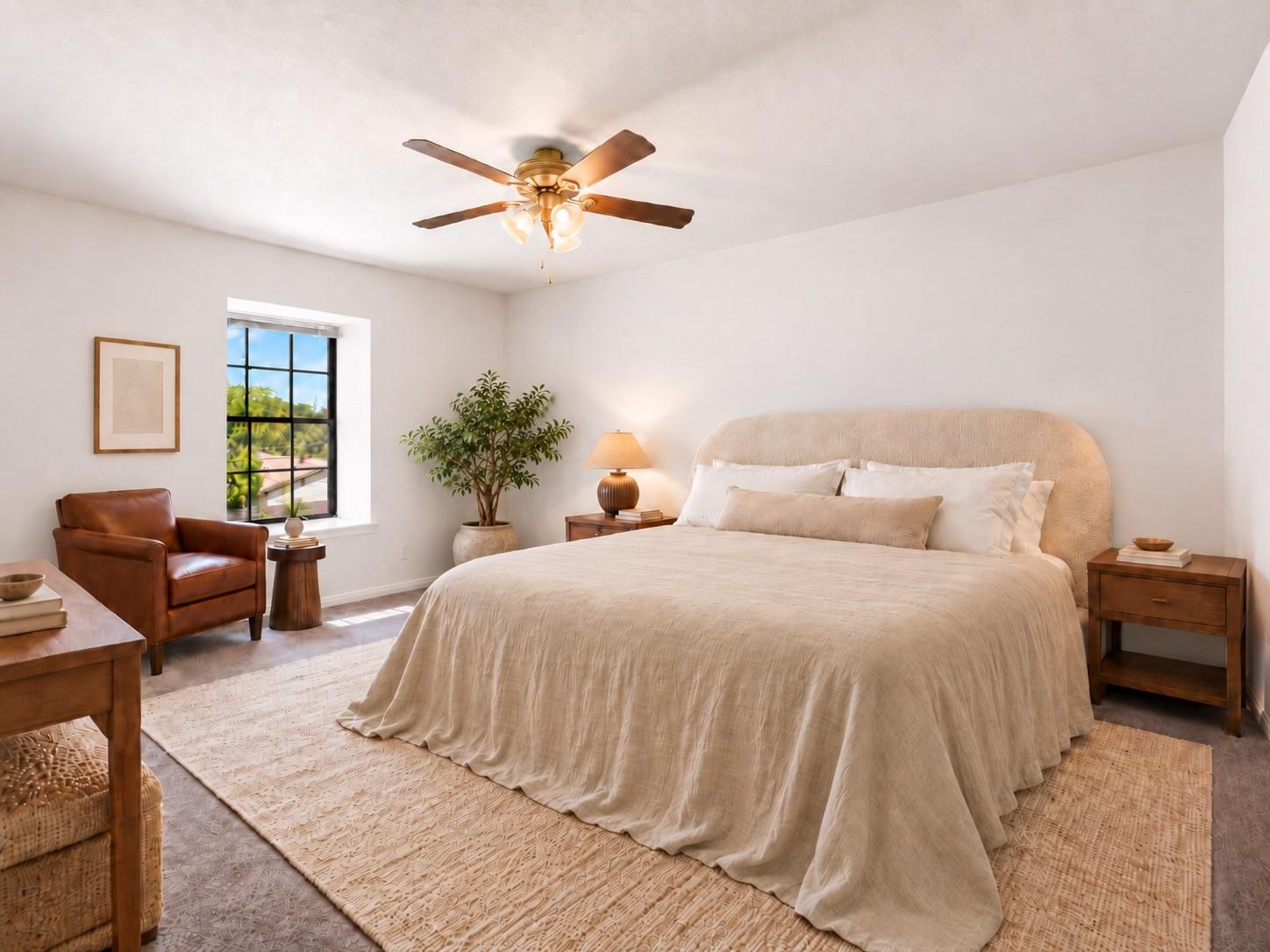 Staged bedroom with a cream bed, brown leather armchair, and black-framed window.