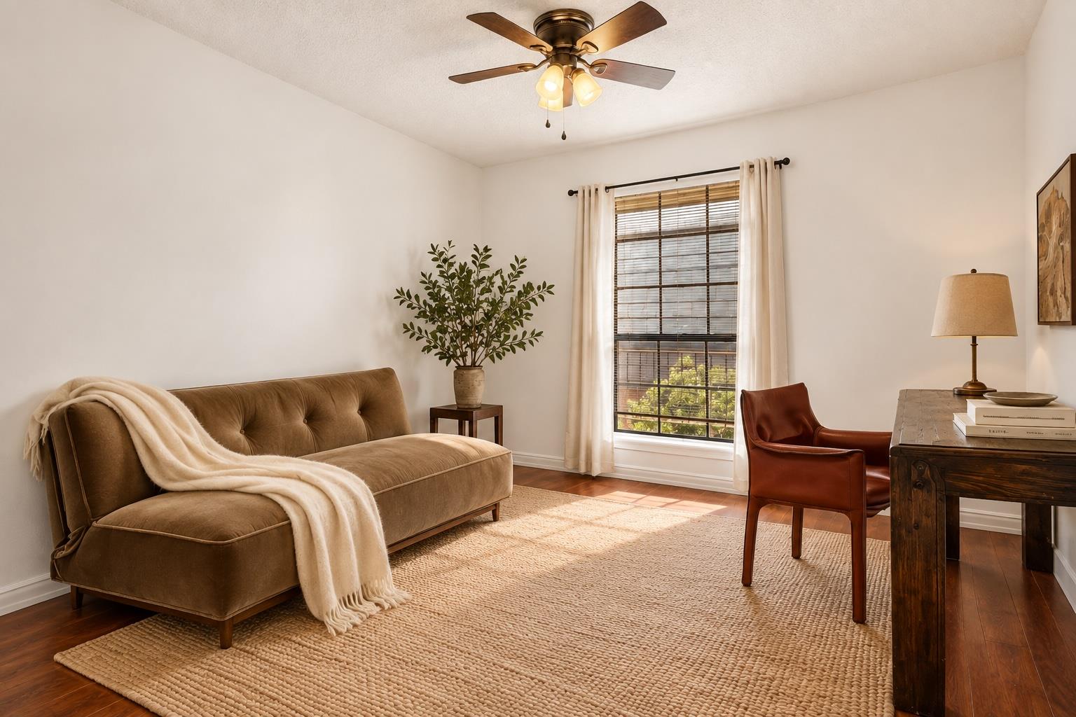 Staged living room with a brown chaise sofa, leather chair, and sunlight through a curtained window.