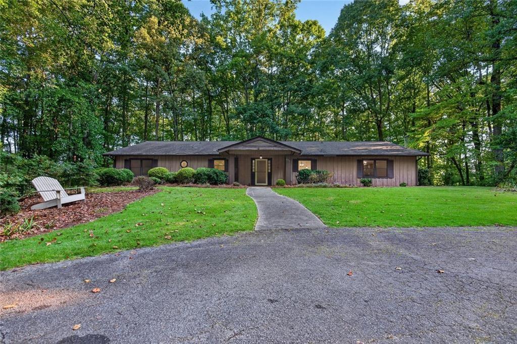 Single-story home with a curved front walkway, green lawn, and mature trees.