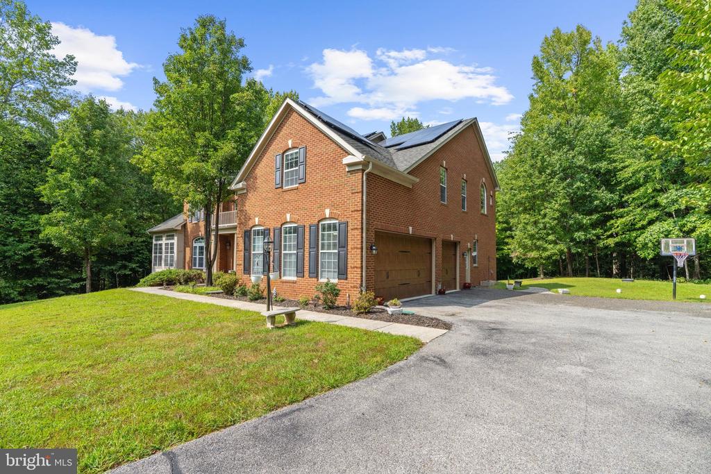 Two-story brick house with rooftop solar panels, an attached garage, and a wide driveway.