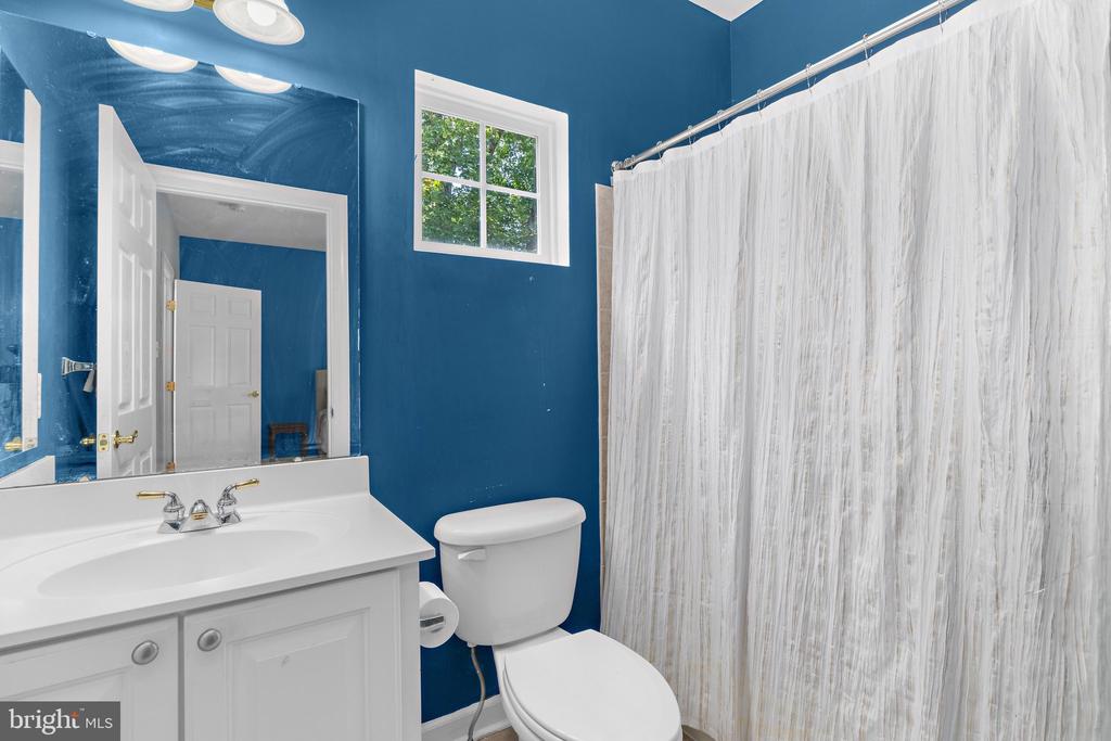 Bathroom with deep blue walls, white vanity, and a shower curtain.