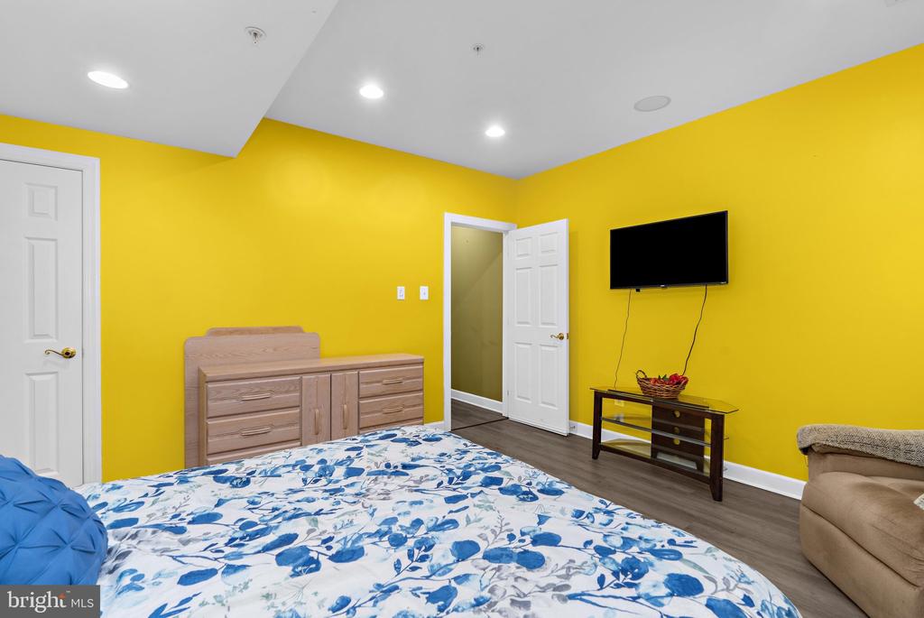 Bedroom with bright yellow walls, a blue-and-white floral bedspread, and a light wood dresser.