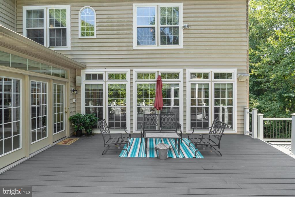 Deck with black patio furniture, a turquoise striped rug, and a red umbrella.