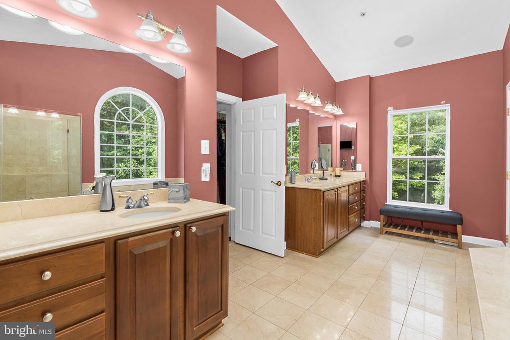 Primary bathroom with two wooden vanities, rose-colored walls, and large windows.