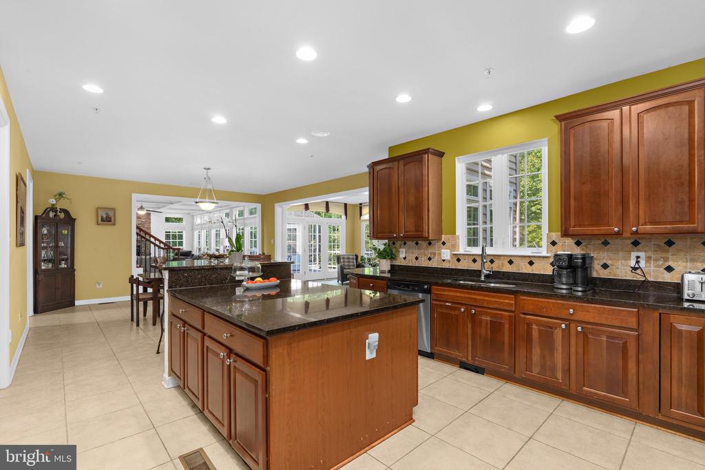 Kitchen with a large granite-topped island, warm wood cabinetry, and an adjoining dining area.