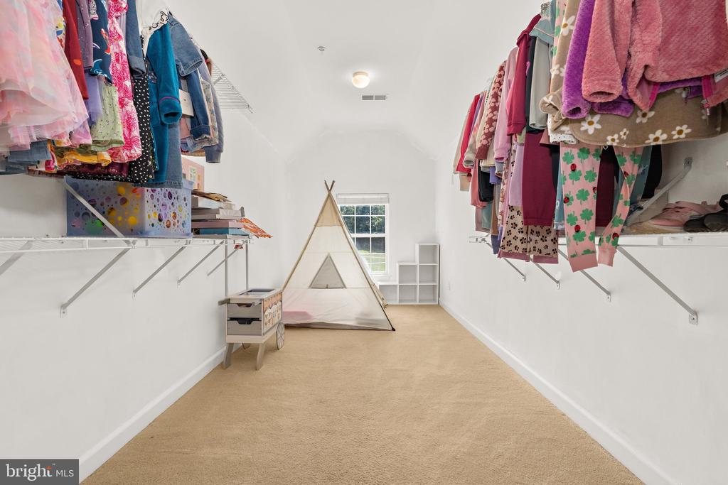 Walk-in closet with clothes on open shelves, a small teepee, and a toy cart.