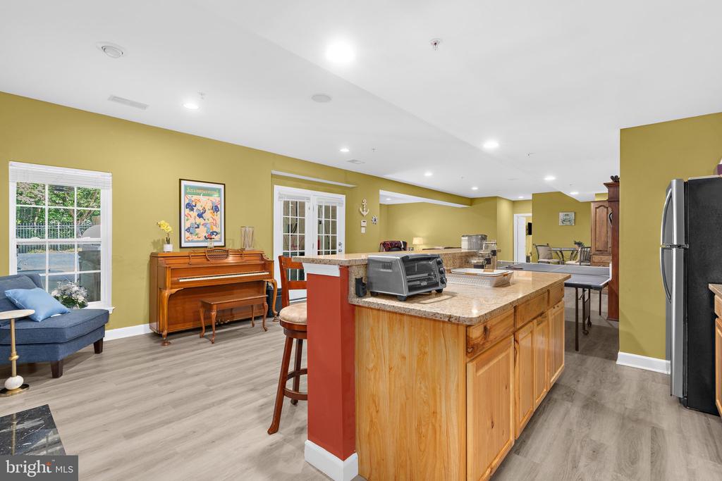 Open-plan kitchen with a large wood island, granite countertop, and piano beside the windows.
