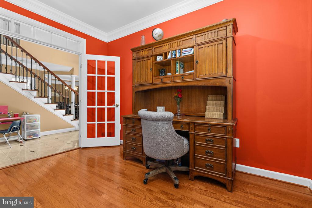 Home office with a wooden built-in desk and hutch, red walls, and an adjacent staircase.