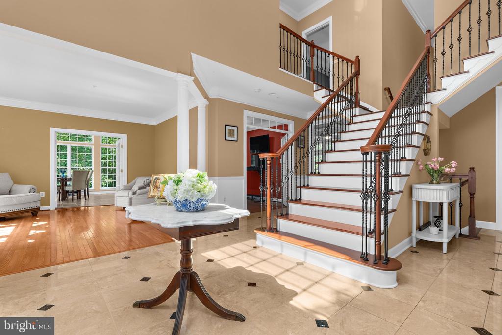 Foyer with a sweeping white staircase, wrought-iron balusters, and a flower-topped console table.