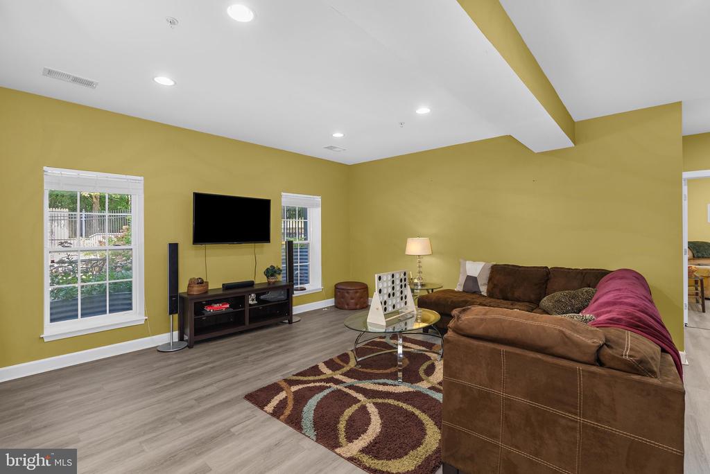 Living room with mustard-yellow walls, a brown sectional, and a patterned rug.