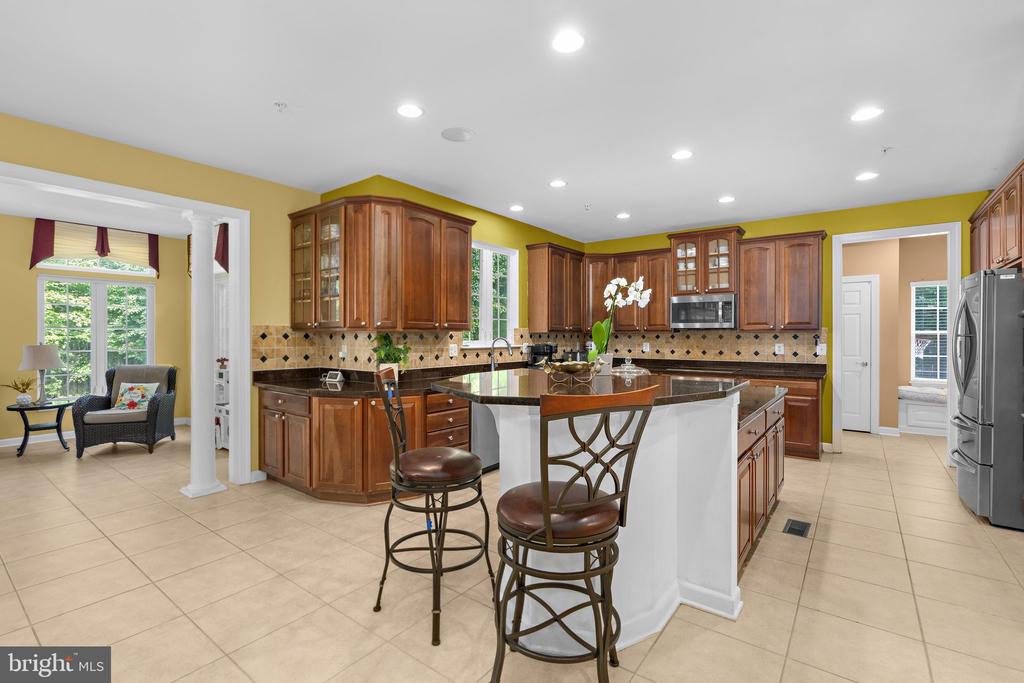 Kitchen with dark wood cabinetry, patterned tile backsplash, central island, and breakfast seating.