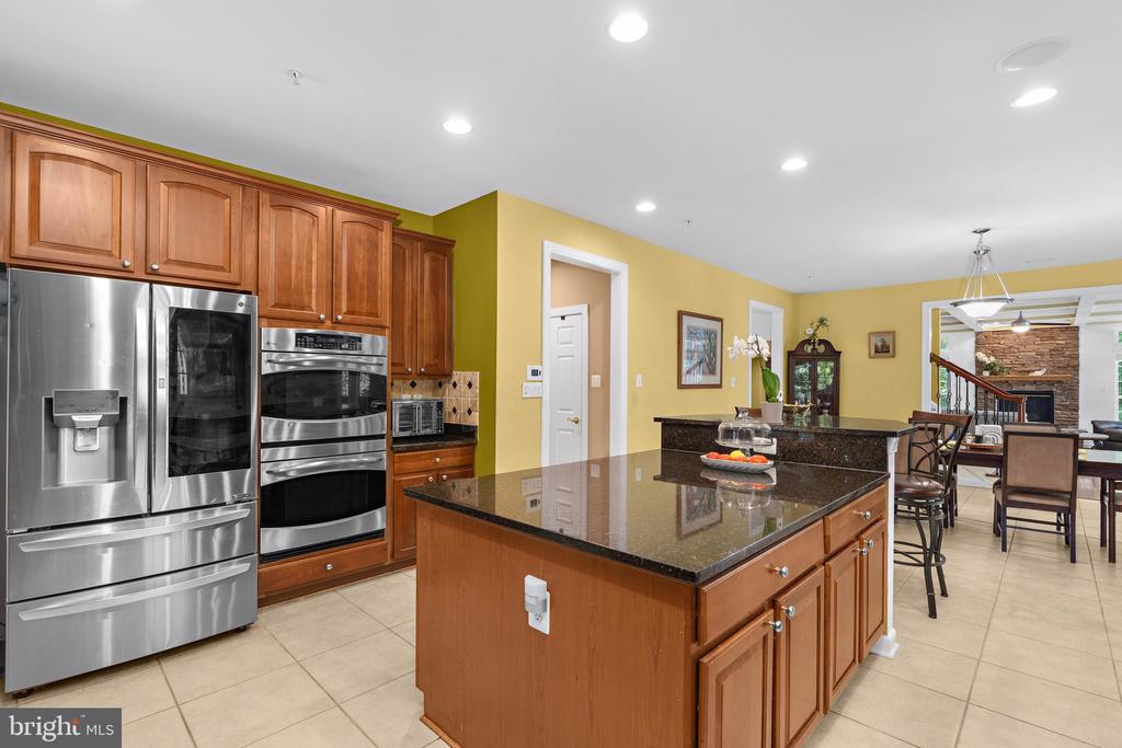 Kitchen with wood cabinetry, stainless steel appliances, and a large granite island.
