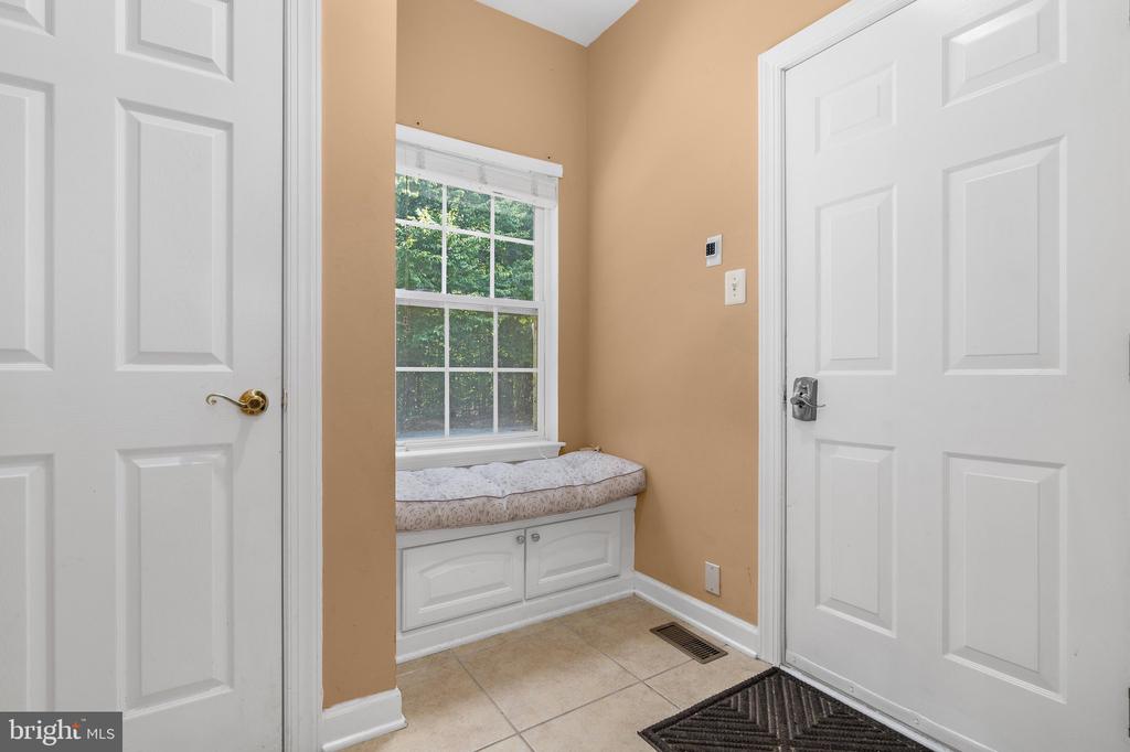Entryway with a built-in window seat, tiled floor, and two white doors.