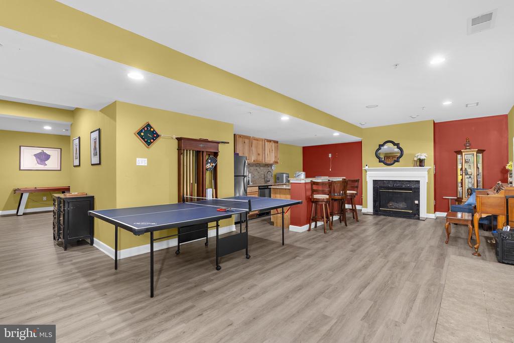 Finished recreation room with a ping-pong table, kitchenette, and fireplace.