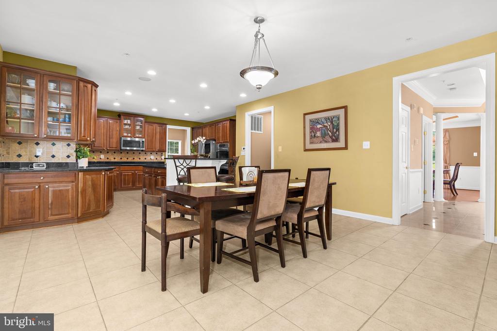 Kitchen and dining area with dark wood cabinetry, tiled backsplash, and a large table with chairs.