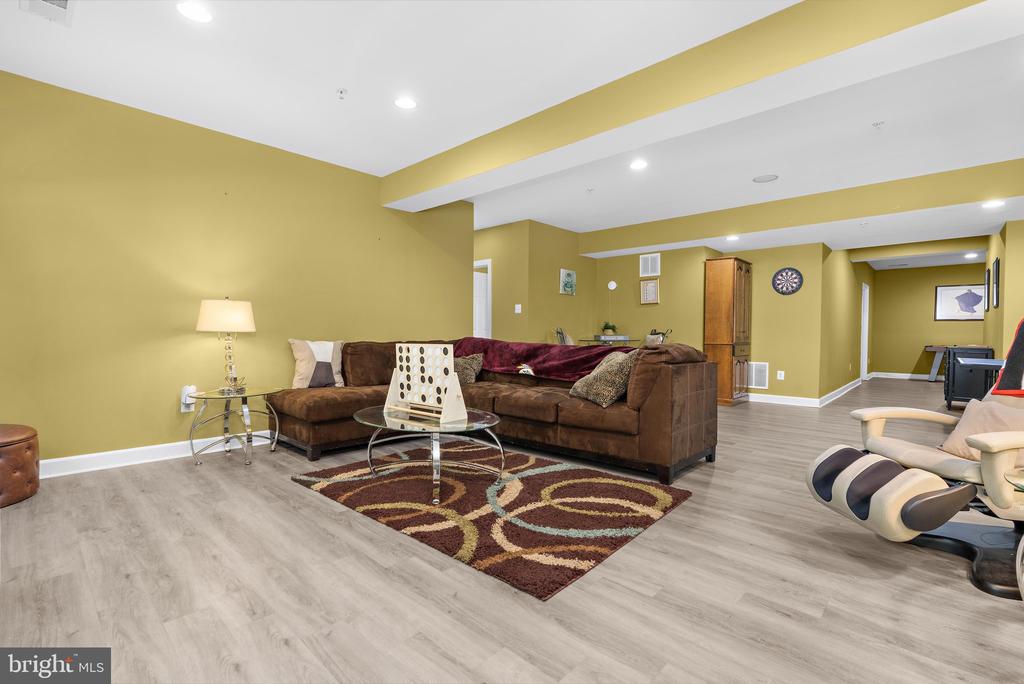Furnished recreation room with a brown sectional, patterned rug, and mustard-yellow walls.