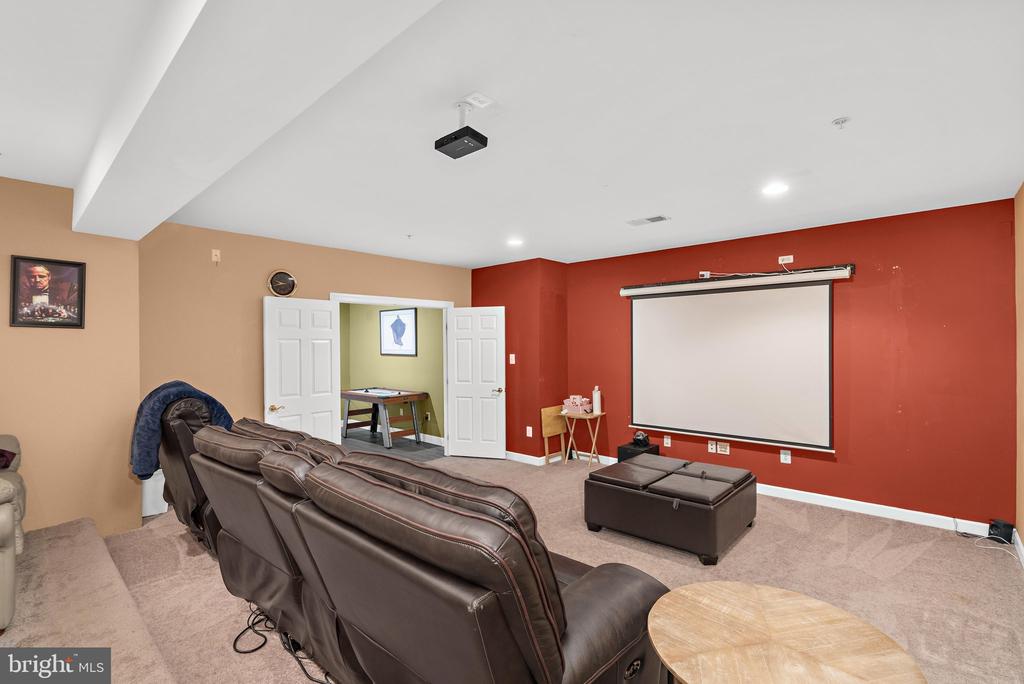 Home theater with leather recliners, a large projection screen, and a ceiling-mounted projector.