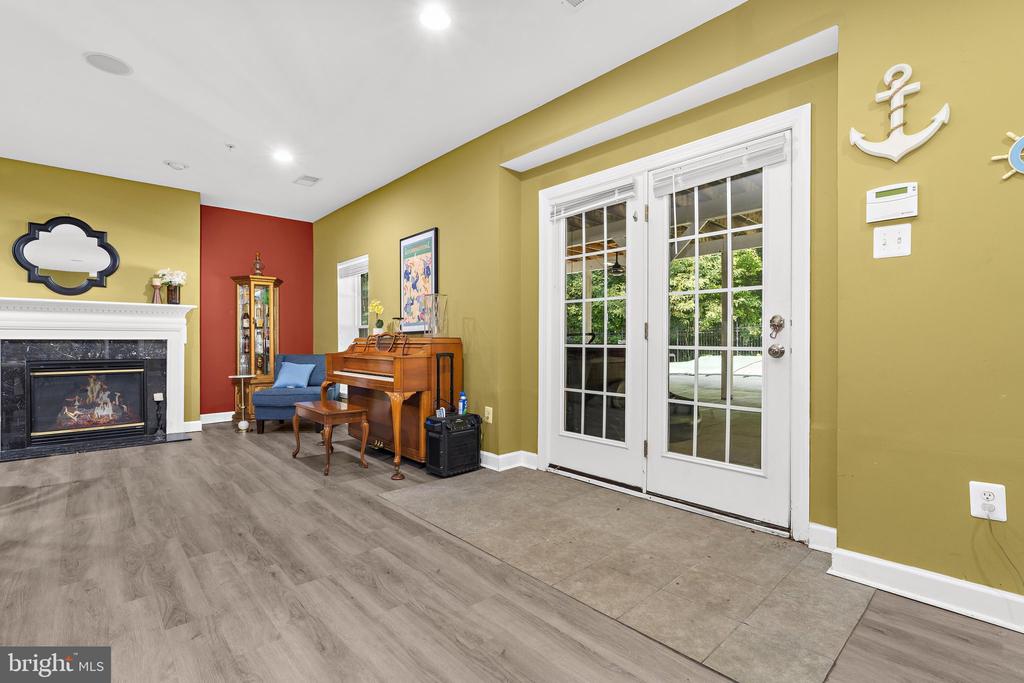 Living room with a fireplace, piano, and French doors opening to a patio.
