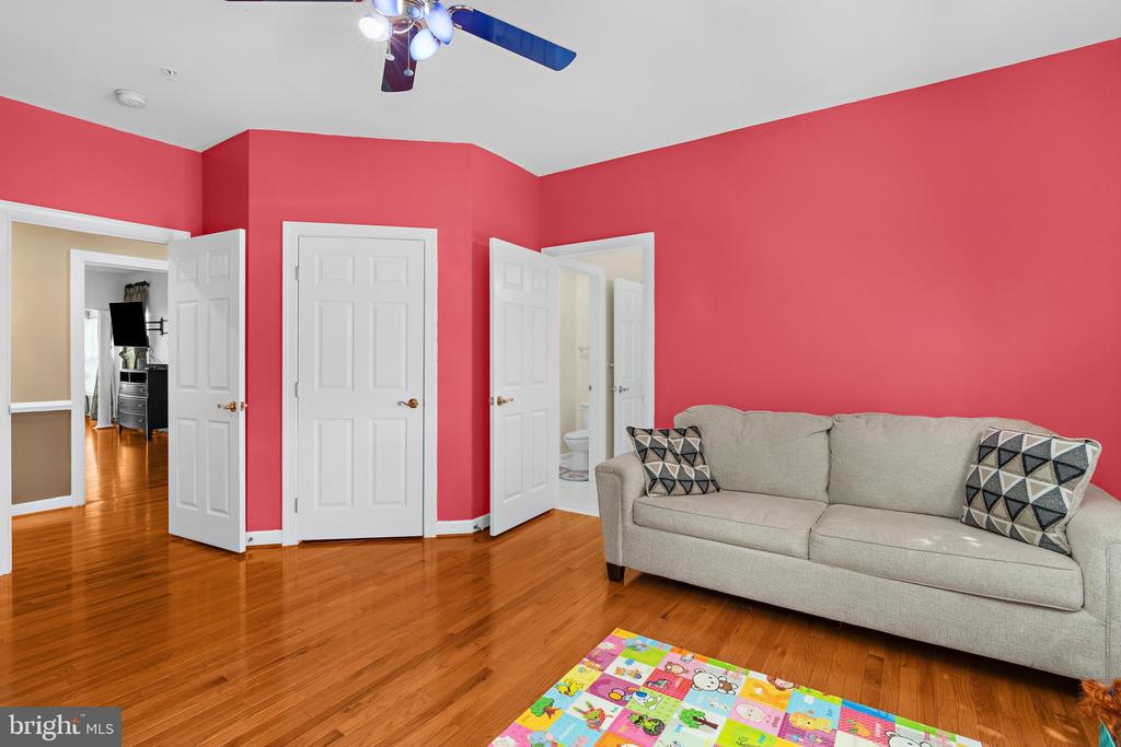 Living room with red walls, hardwood floors, and a beige sofa.