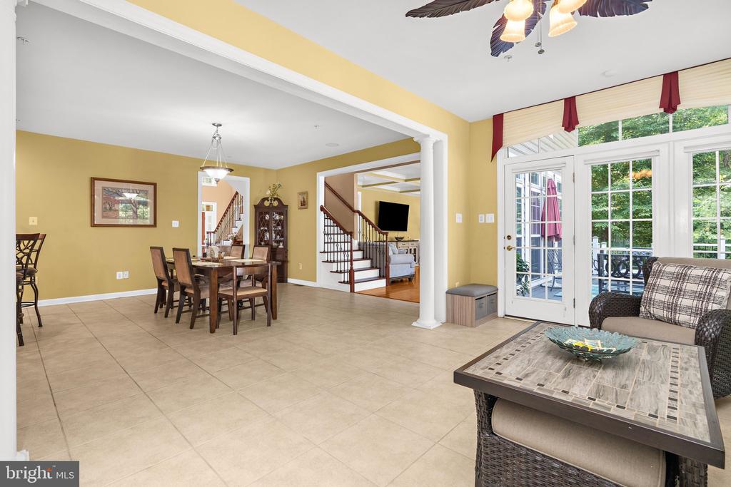 Open dining and sitting area with yellow walls, tiled floors, and glass doors to a deck.
