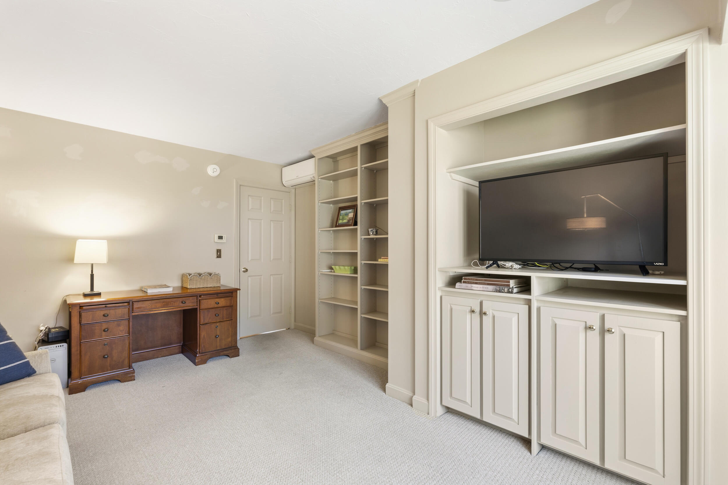 Furnished den with a wooden desk and built-in television cabinet.