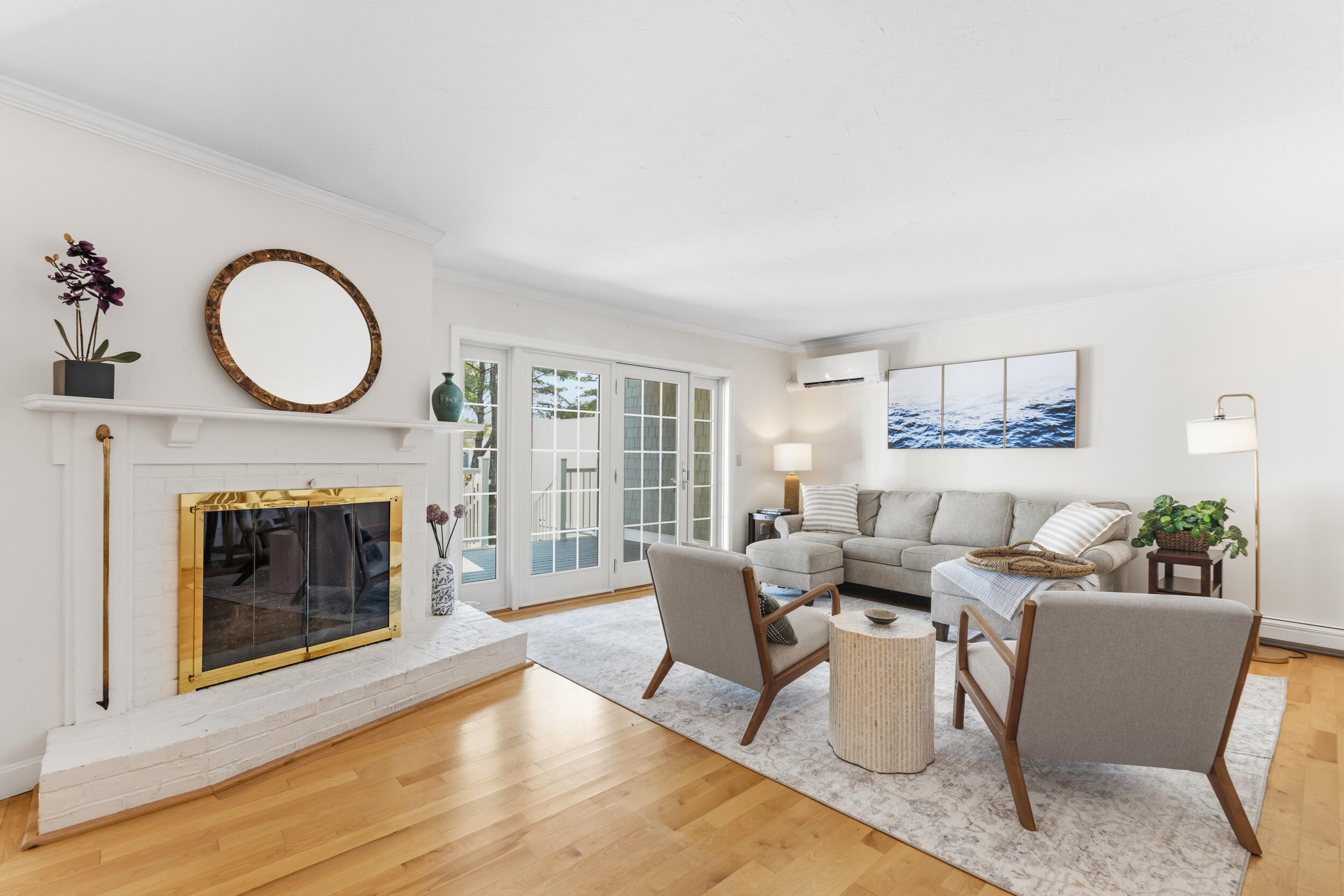 Living room with a brass-trimmed fireplace, French doors, gray sectional, and hardwood floors.