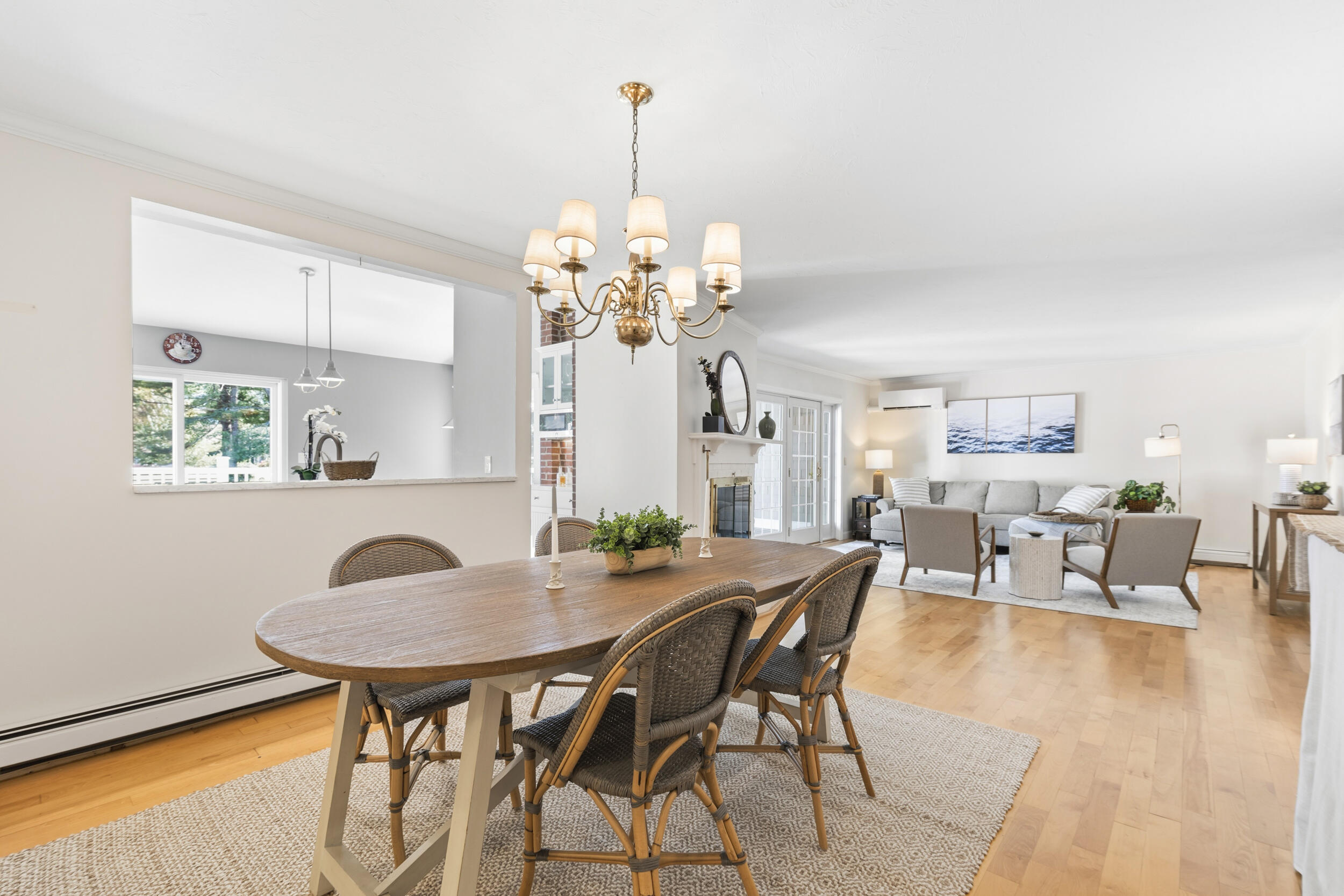 Open-plan dining and living room with a wooden table, woven chairs, gray sofa, and fireplace.