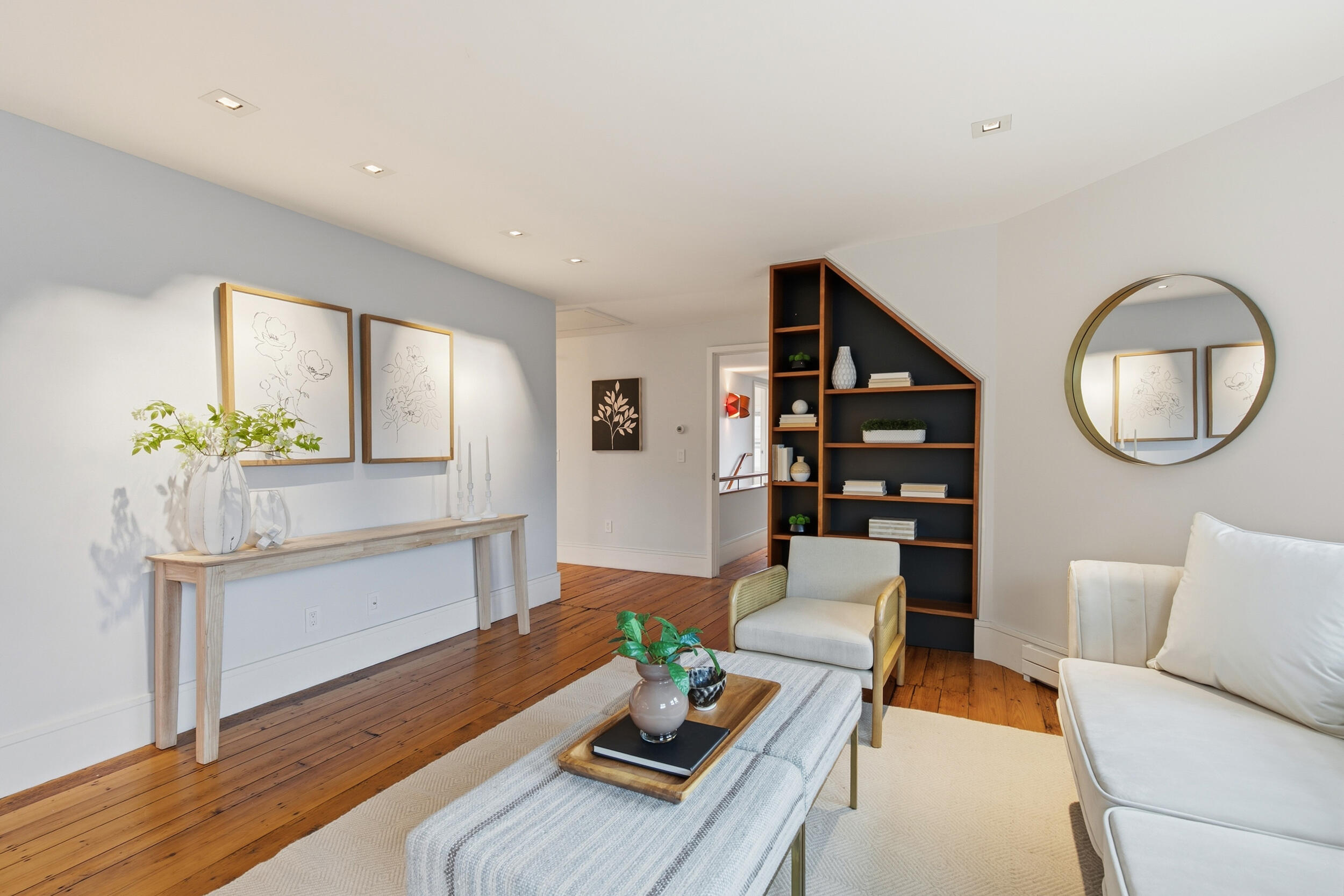 Living room with wide-plank wood floors, built-in shelving, and neutral furnishings.