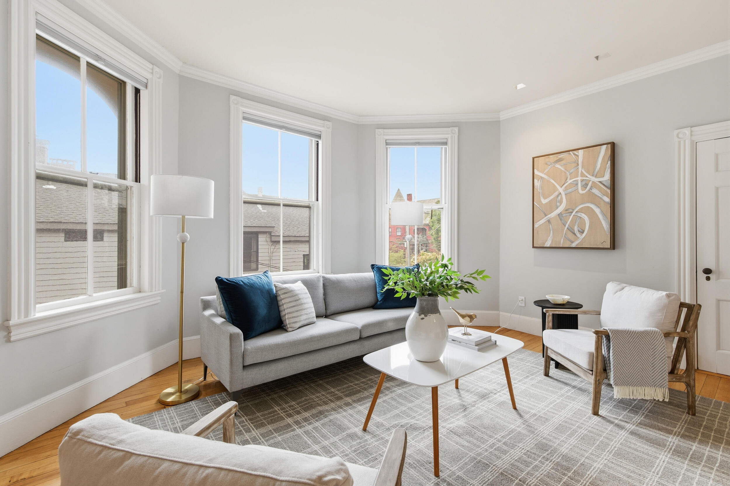 Living room with tall windows, a gray sofa, and a bright seating area.