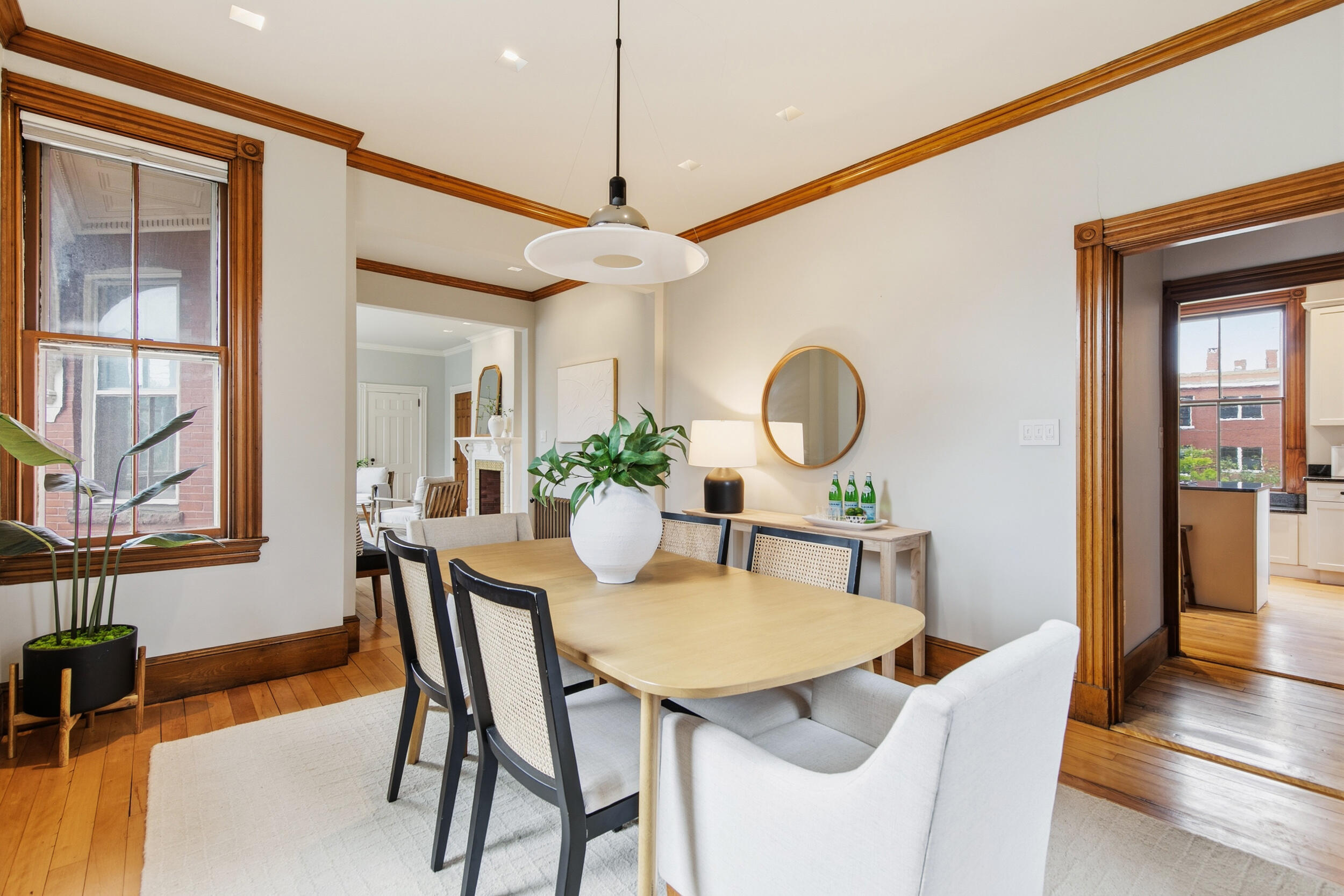 Dining room with a light wood table, ornate wood trim, and tall windows.